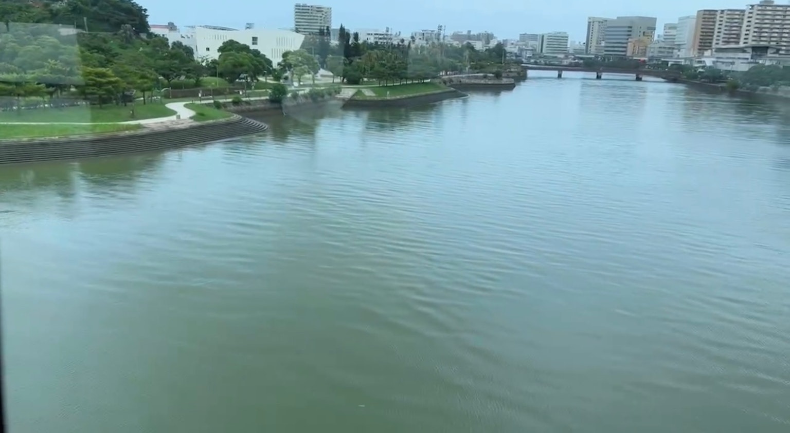 A serene view of a river reflecting cityscape and greenery