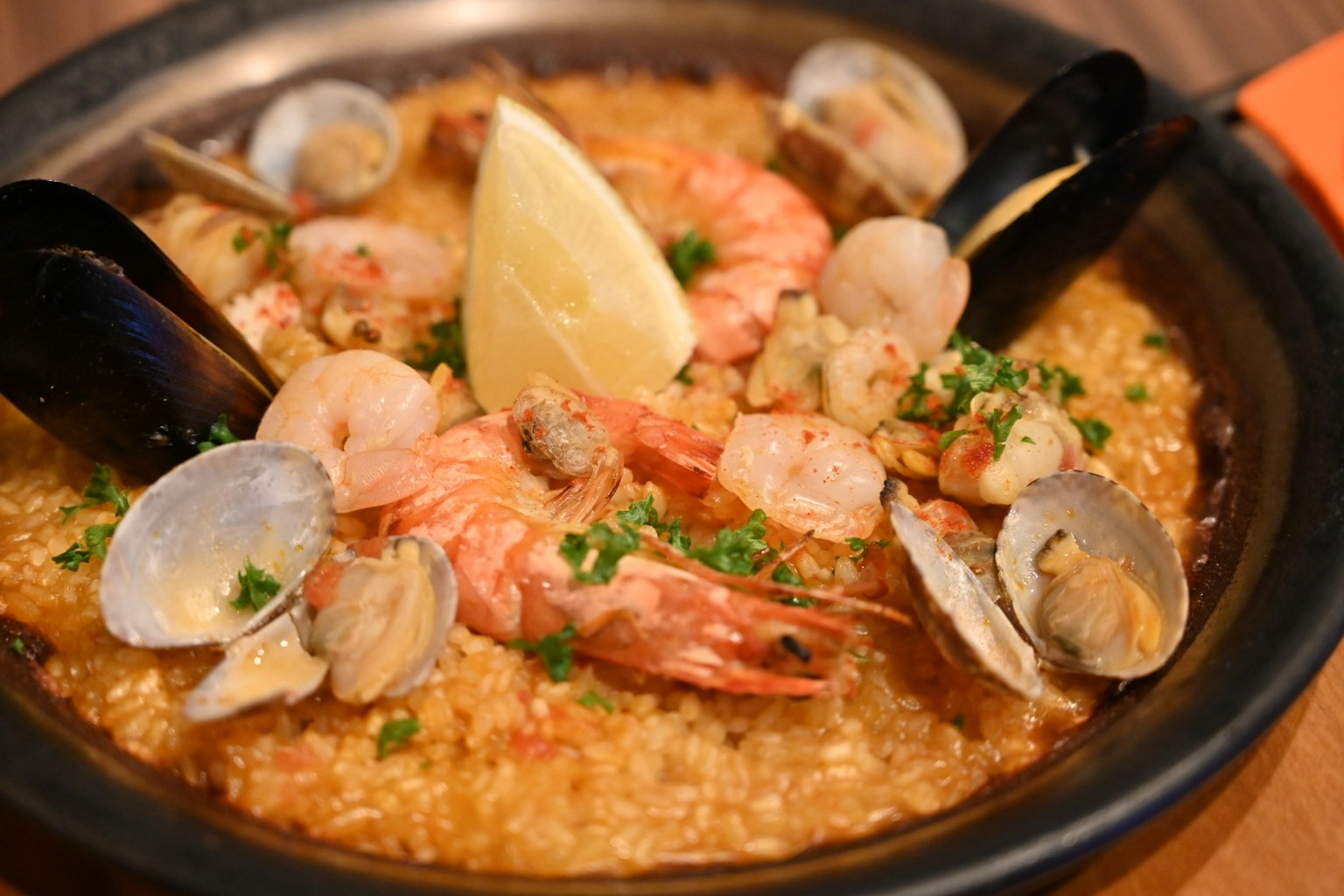 Paella di frutti di mare con gamberi e vongole guarnita con fette di limone