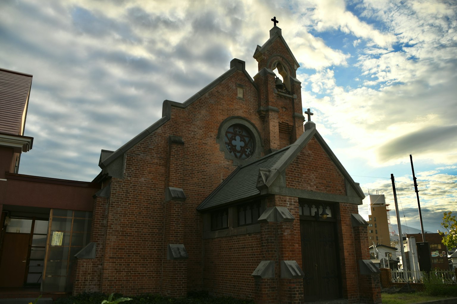 Nhà thờ gạch với tháp đồng hồ và bầu trời nhiều mây