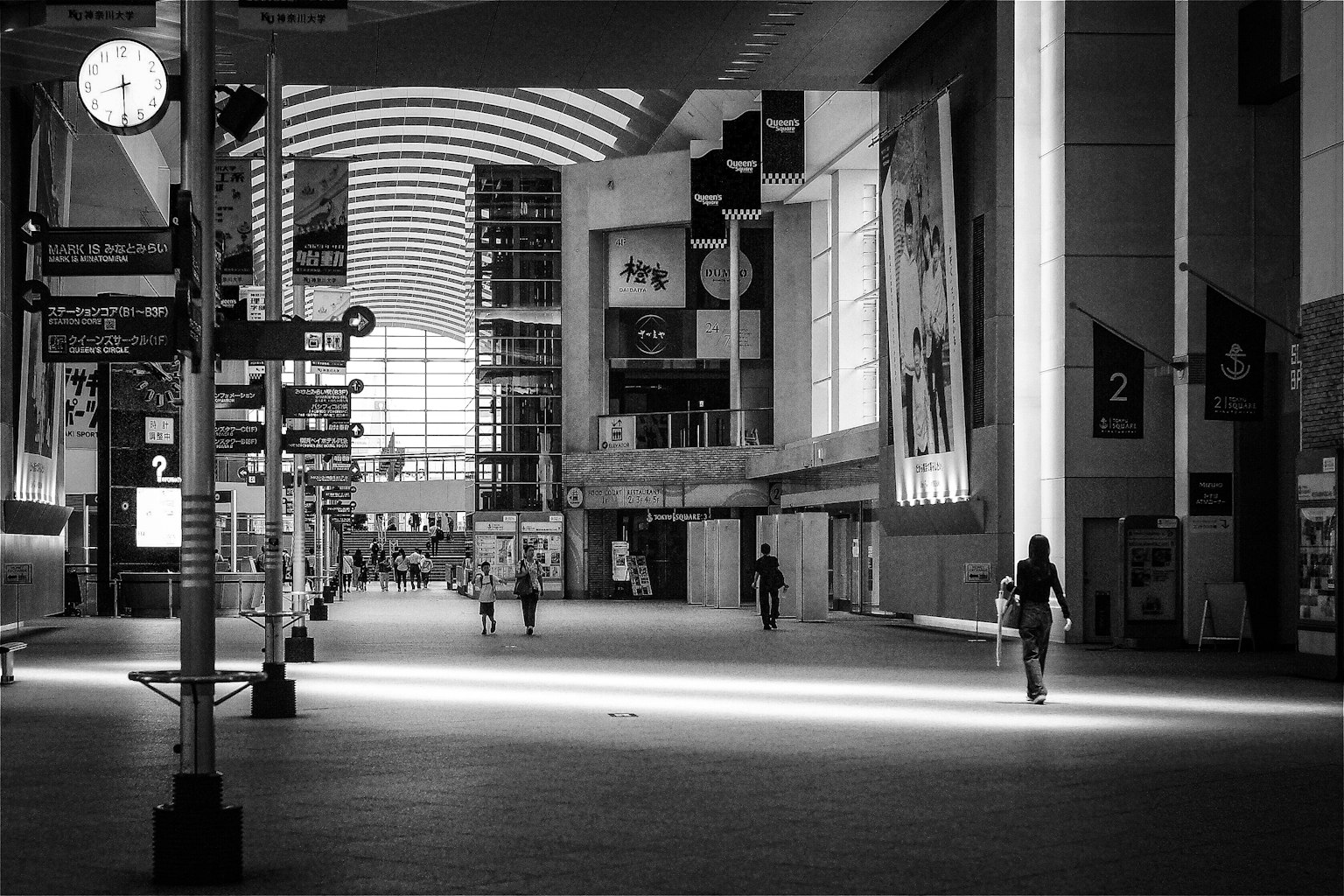 Interior of an empty commercial space with people walking Light streaming through large windows