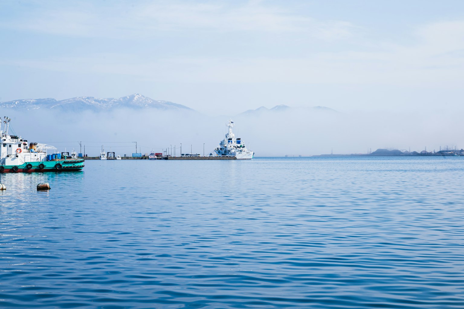 Ruhige Wasseroberfläche mit Booten und entfernten Bergen