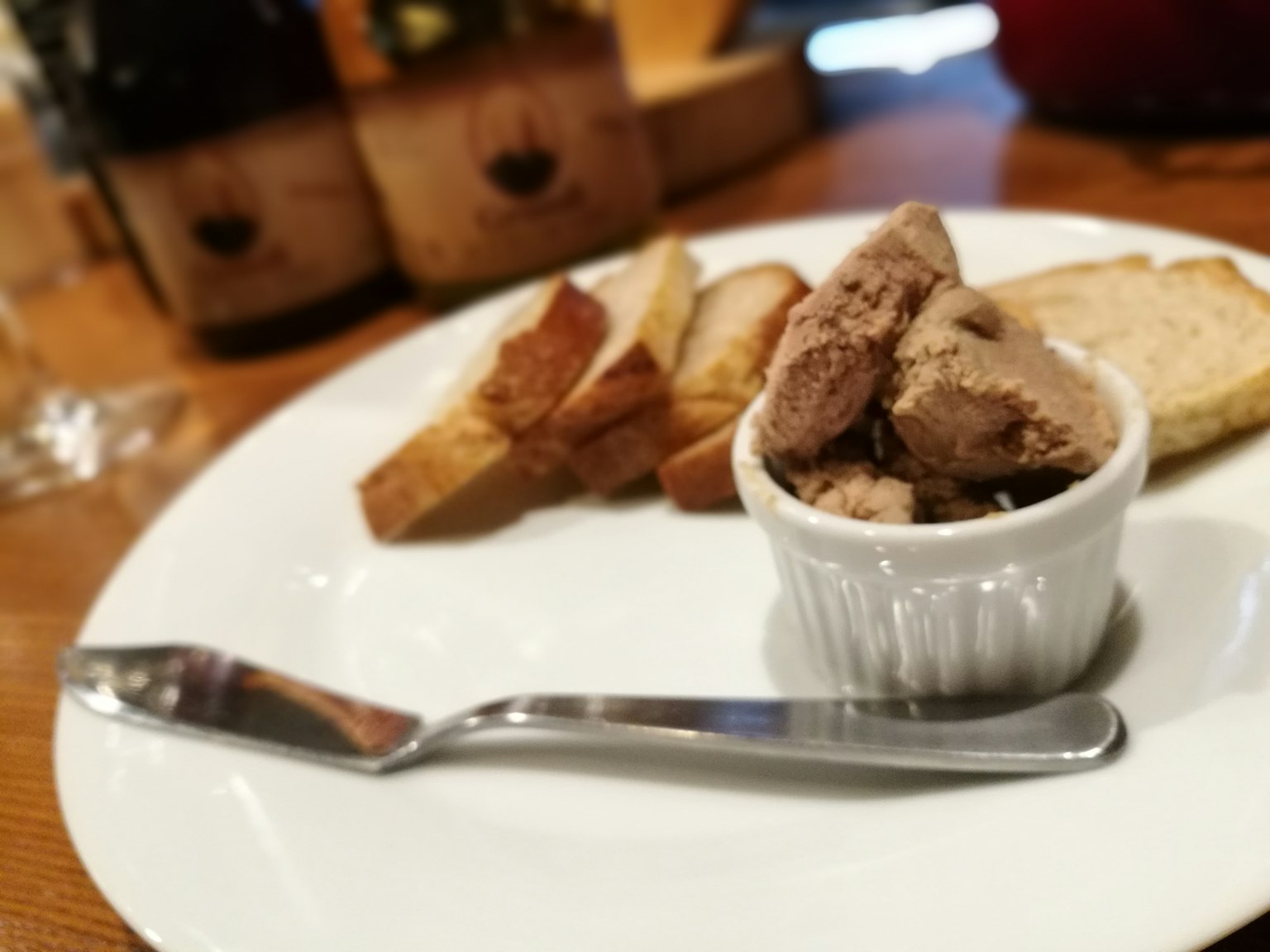 一個盤子上有烤麵包、麵包和一小碗鵝肝醬