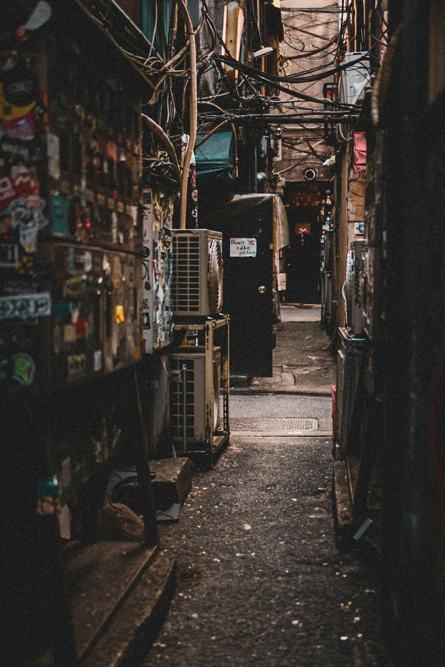 Narrow alley with walls covered in stickers and visible electrical wiring
