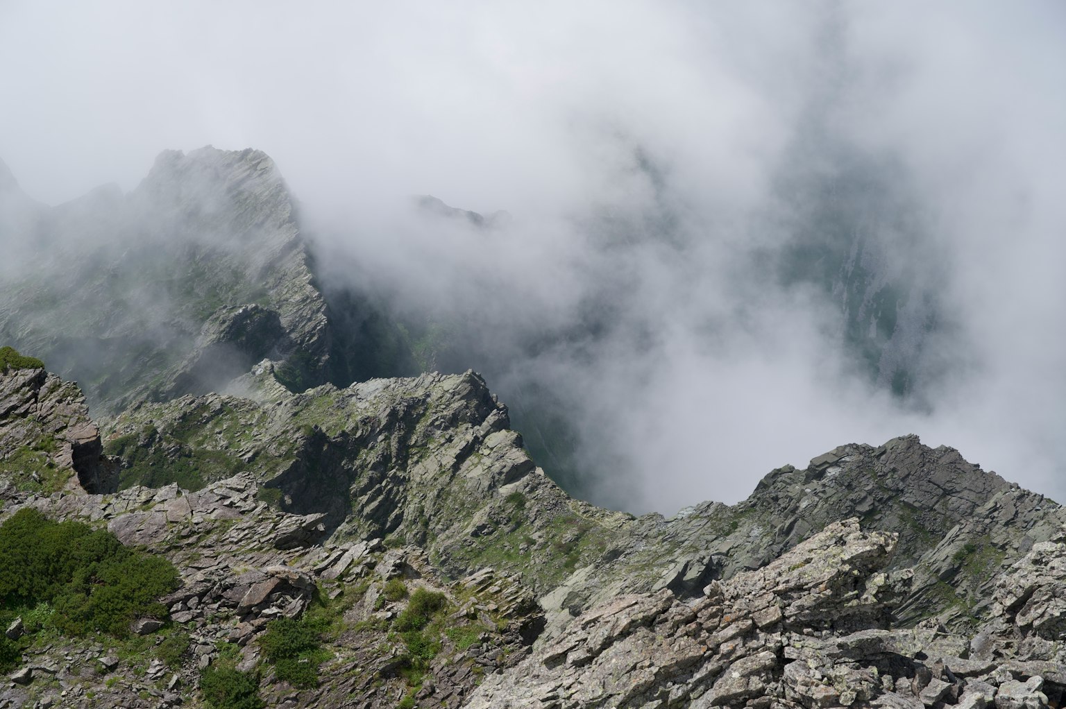 Paisaje montañoso brumoso con picos de roca afilados y vegetación