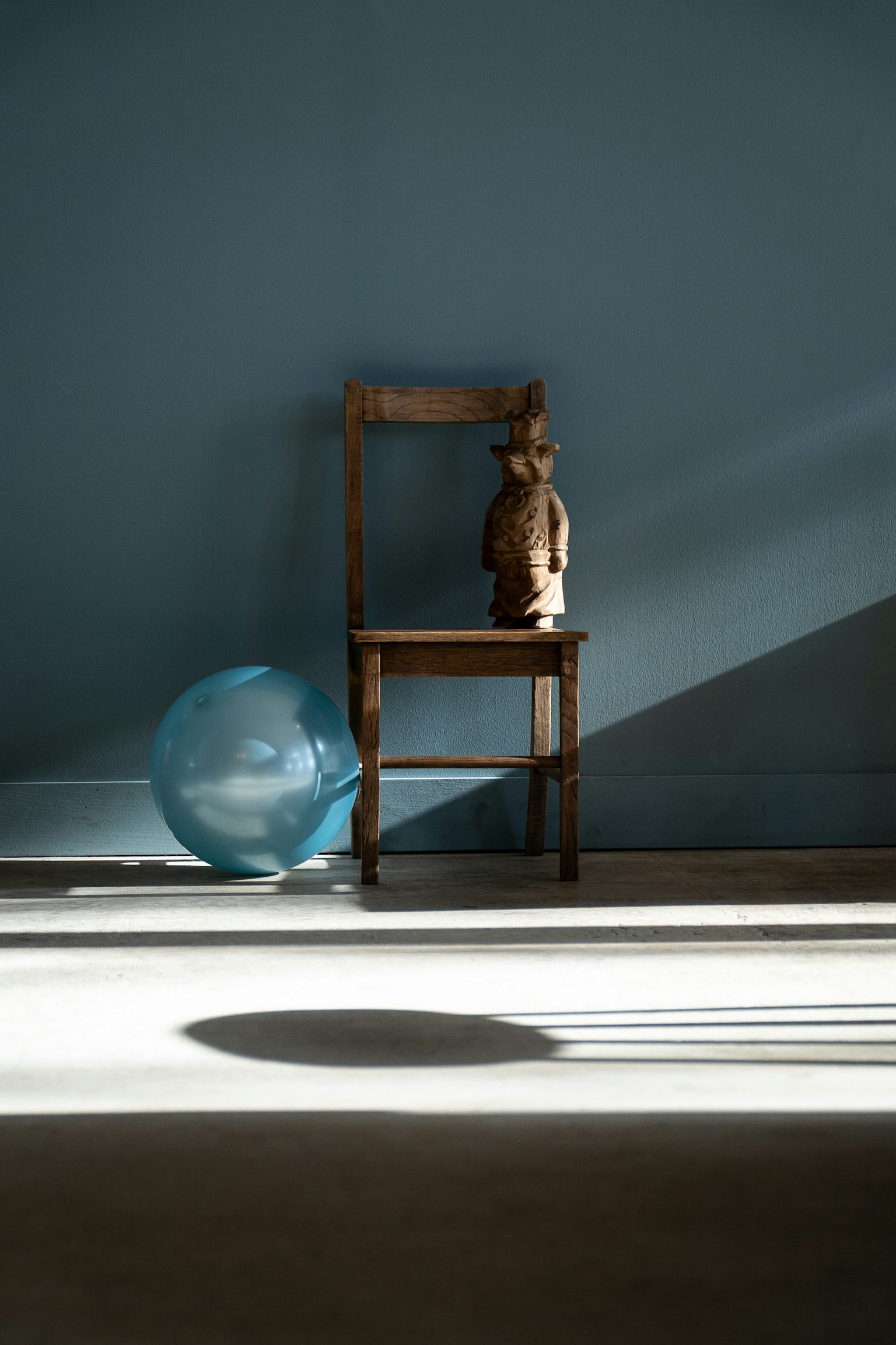 青い壁の前に置かれた木製の椅子と青い風船がある部屋の光の影
