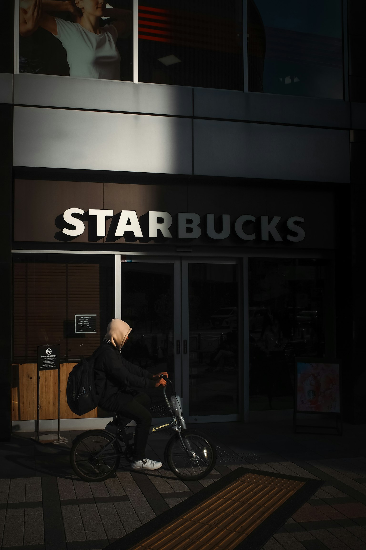 Người đi xe đạp trước Starbucks ánh sáng mặt trời sáng và bóng râm