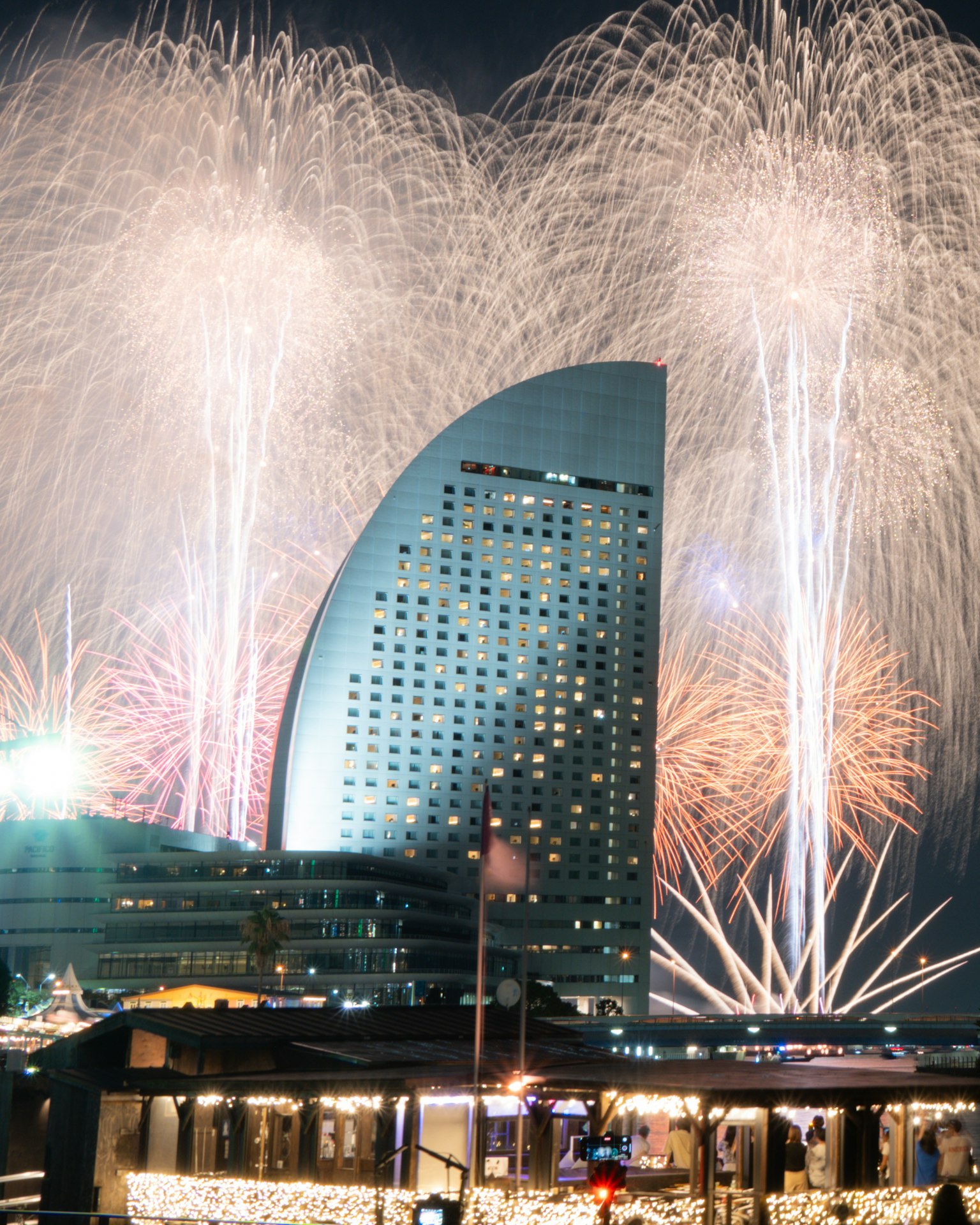 Fuochi d'artificio illuminano il cielo notturno sopra un edificio simbolo di Yokohama