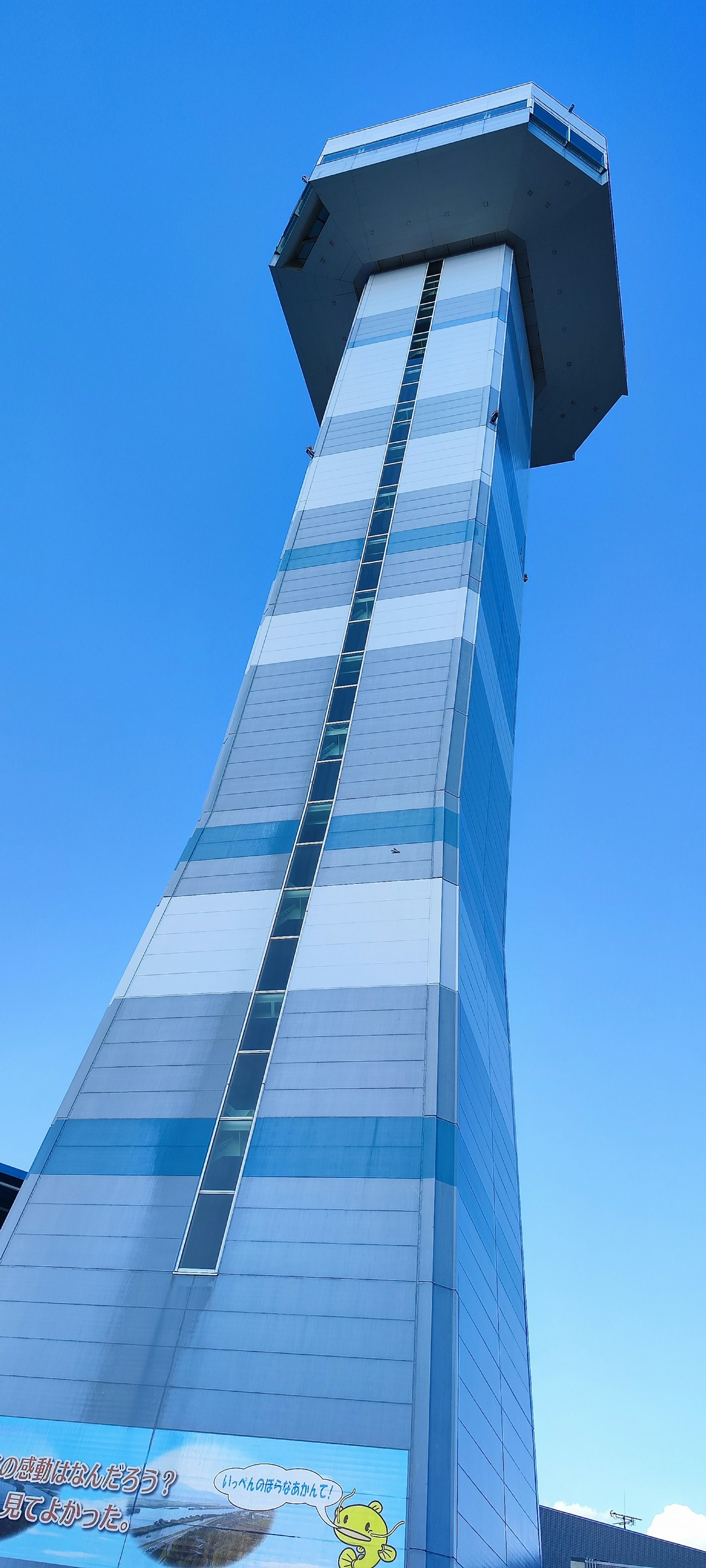 A tall blue and white striped tower under a clear blue sky