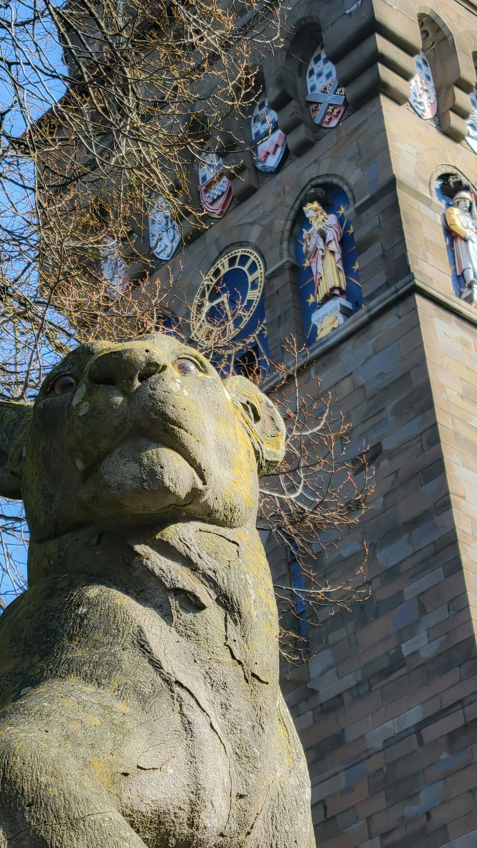 Statue de lion en pierre devant une horloge avec des décorations colorées