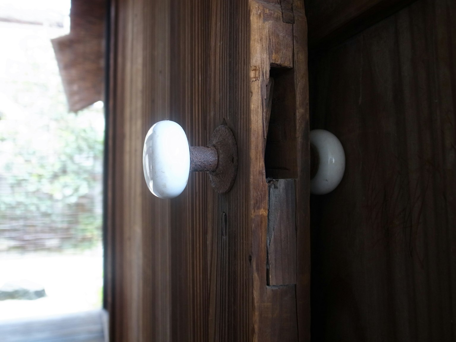 Maniglia bianca e fessura sul lato di una porta in legno