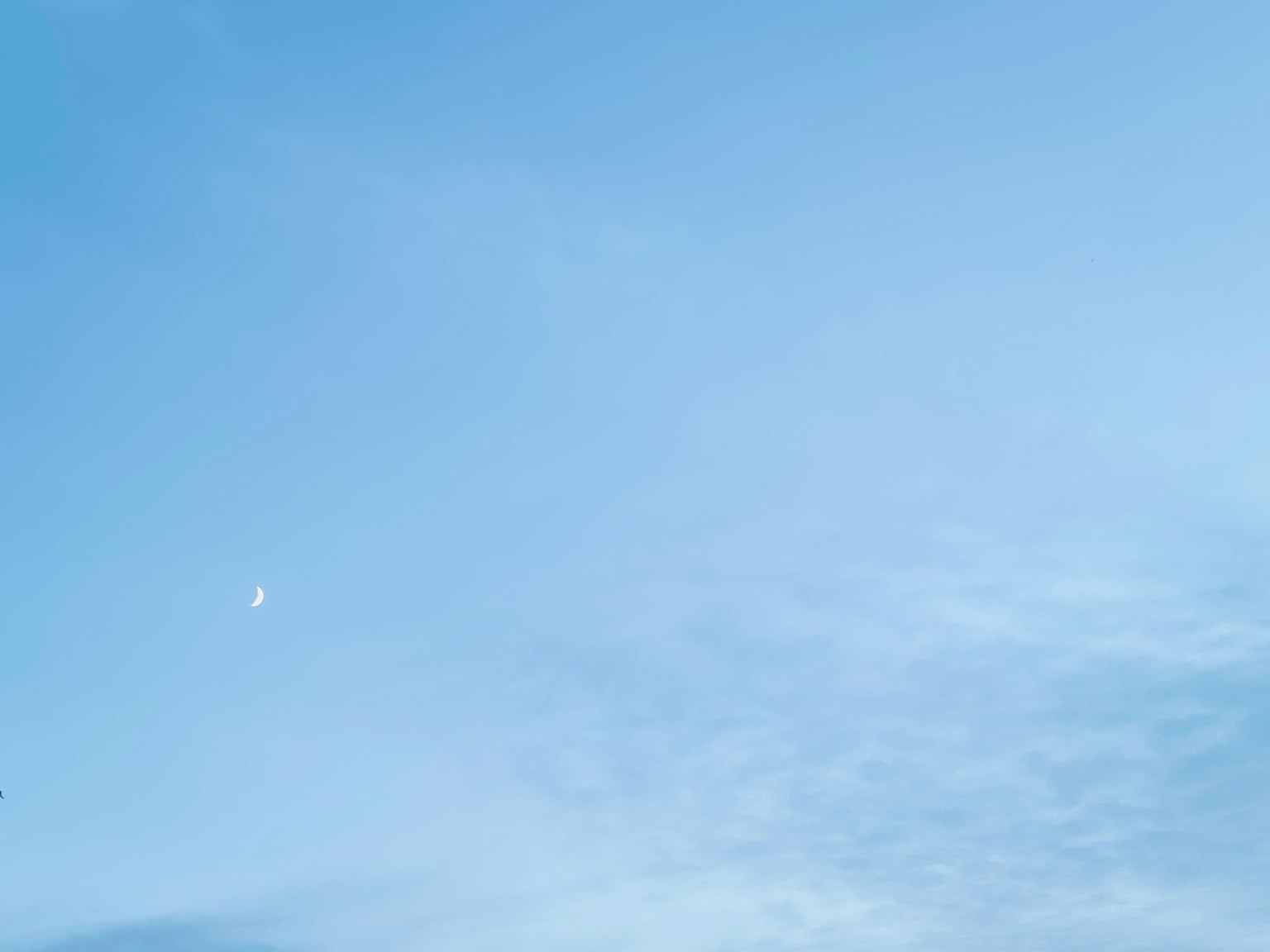 Cielo blu chiaro con una luna crescente e nuvole sottili