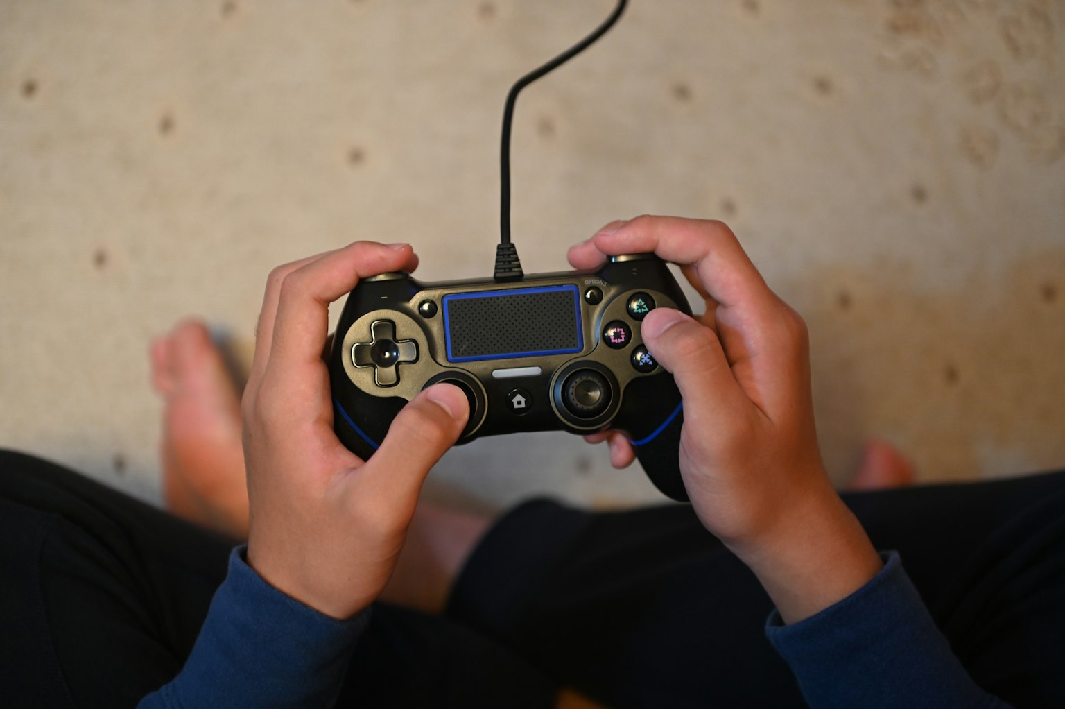 Bàn tay của trẻ cầm tay cầm game với đôi chân trần nhìn thấy