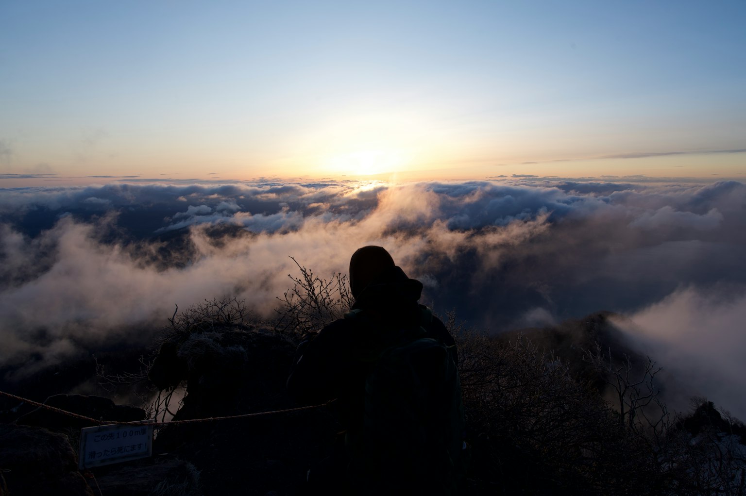 Orang yang melihat matahari terbit dari puncak gunung dengan lautan awan