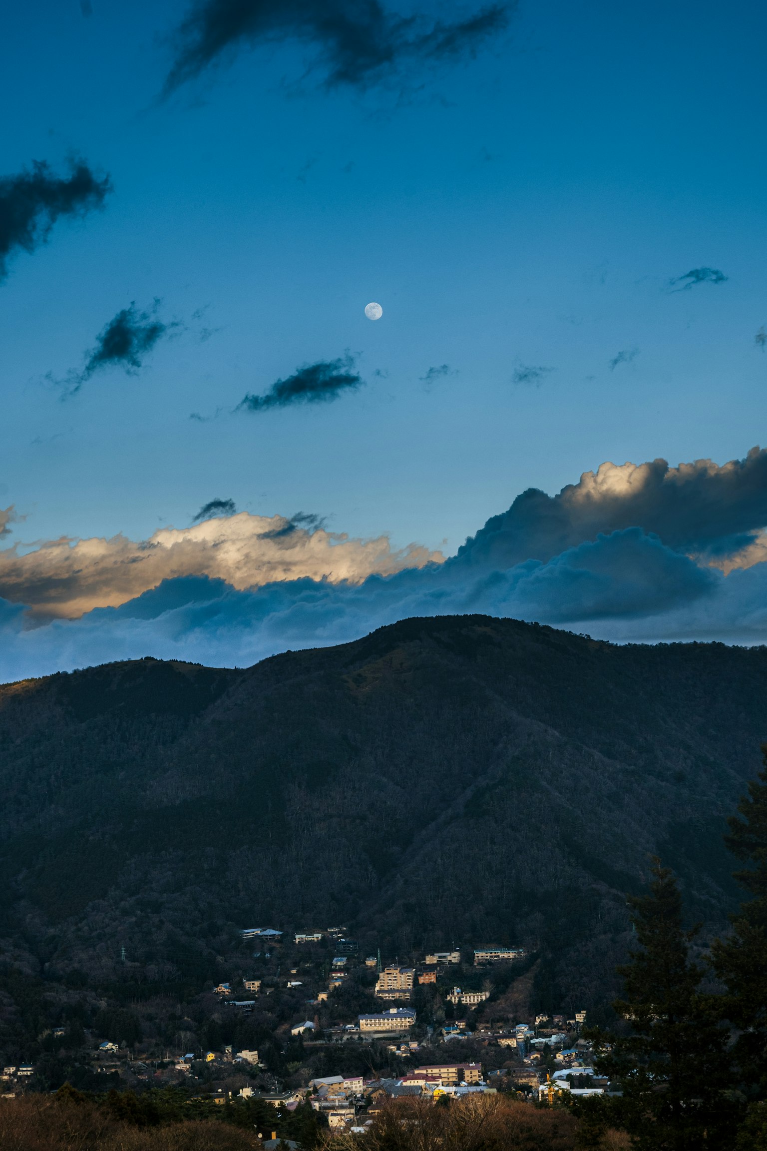 Vista panoramica delle montagne sotto un cielo blu con luna visibile