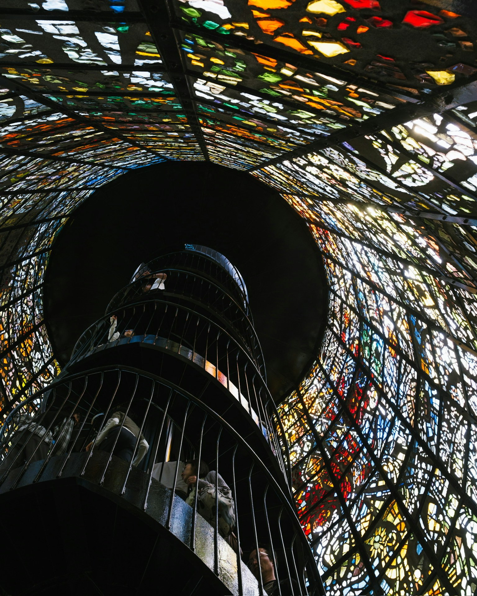 Vue en regardant vers le haut à l'intérieur d'une structure cylindrique ornée de vitraux colorés