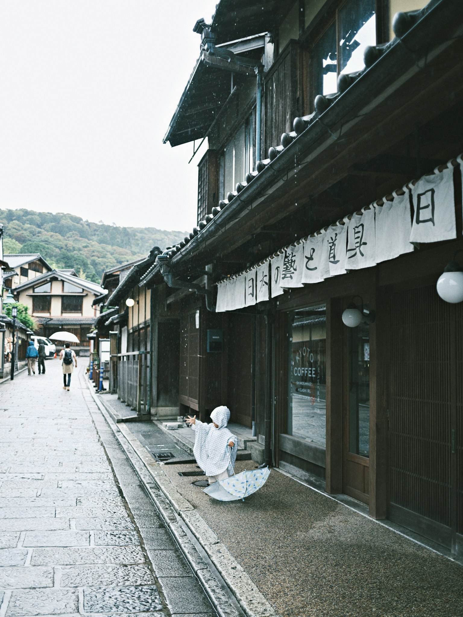 Escena de calle japonesa histórica con una persona vestida de blanco sentada