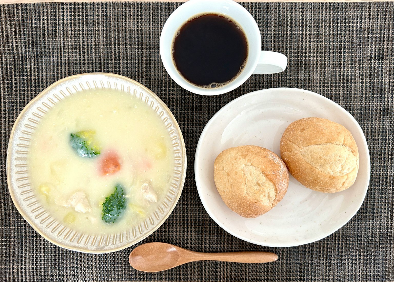 Table de petit-déjeuner avec un bol de soupe et deux petits pains accompagnés d'une tasse de café