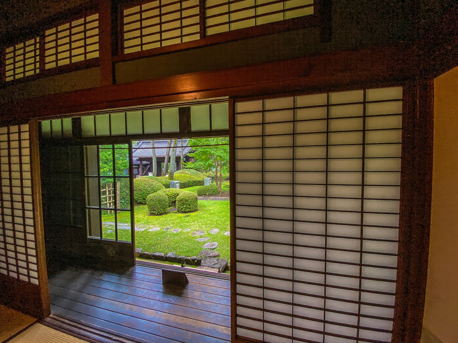 View of a Japanese traditional house interior overlooking a garden featuring shoji and wooden frames