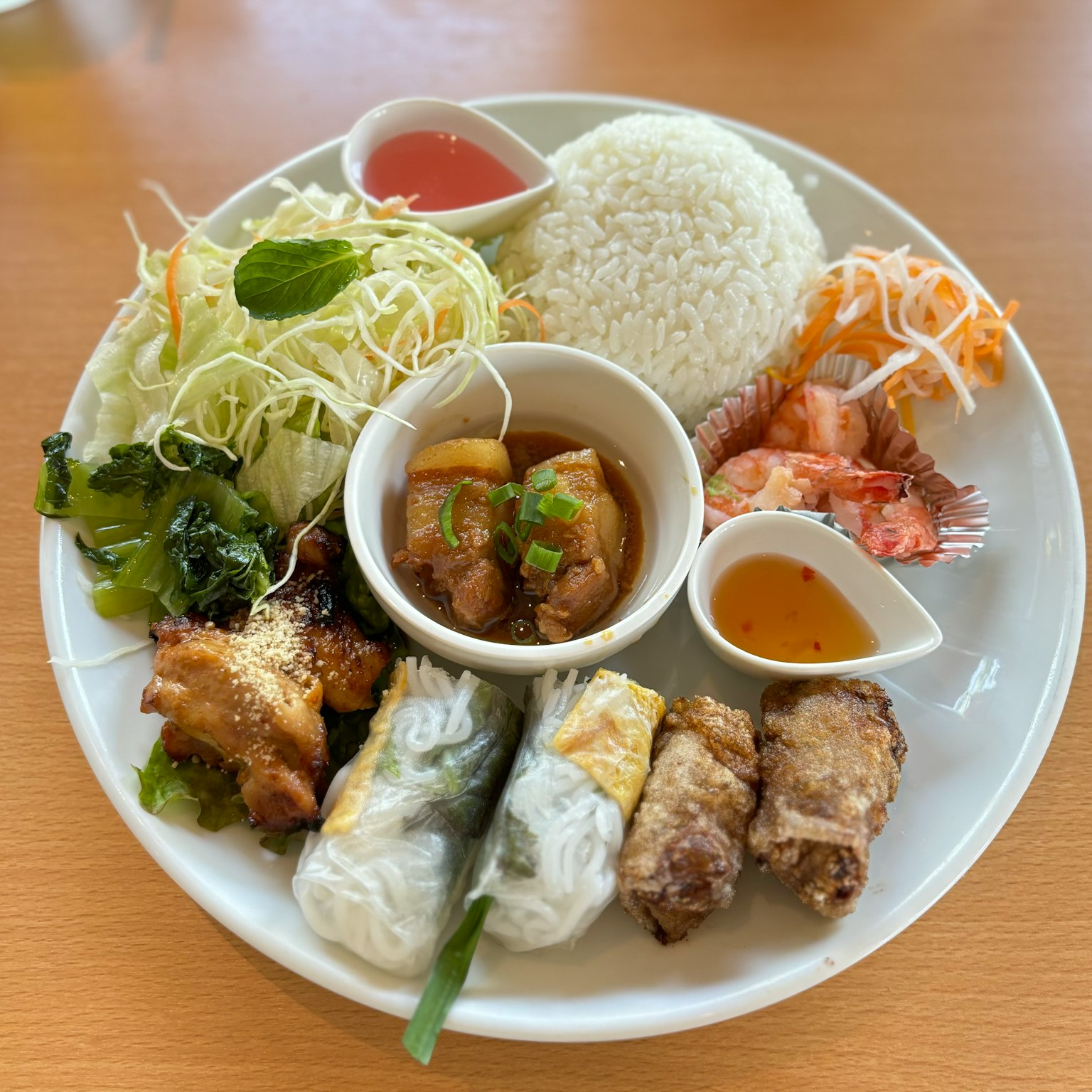 一盘多样的菜肴包括白米饭和沙拉炖菜和虾春卷和炸物