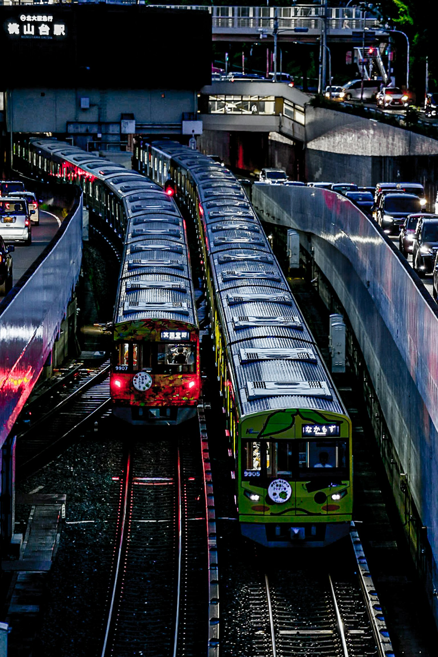 Vue de plusieurs trains se croisant avec des voitures colorées circulant sur des rails