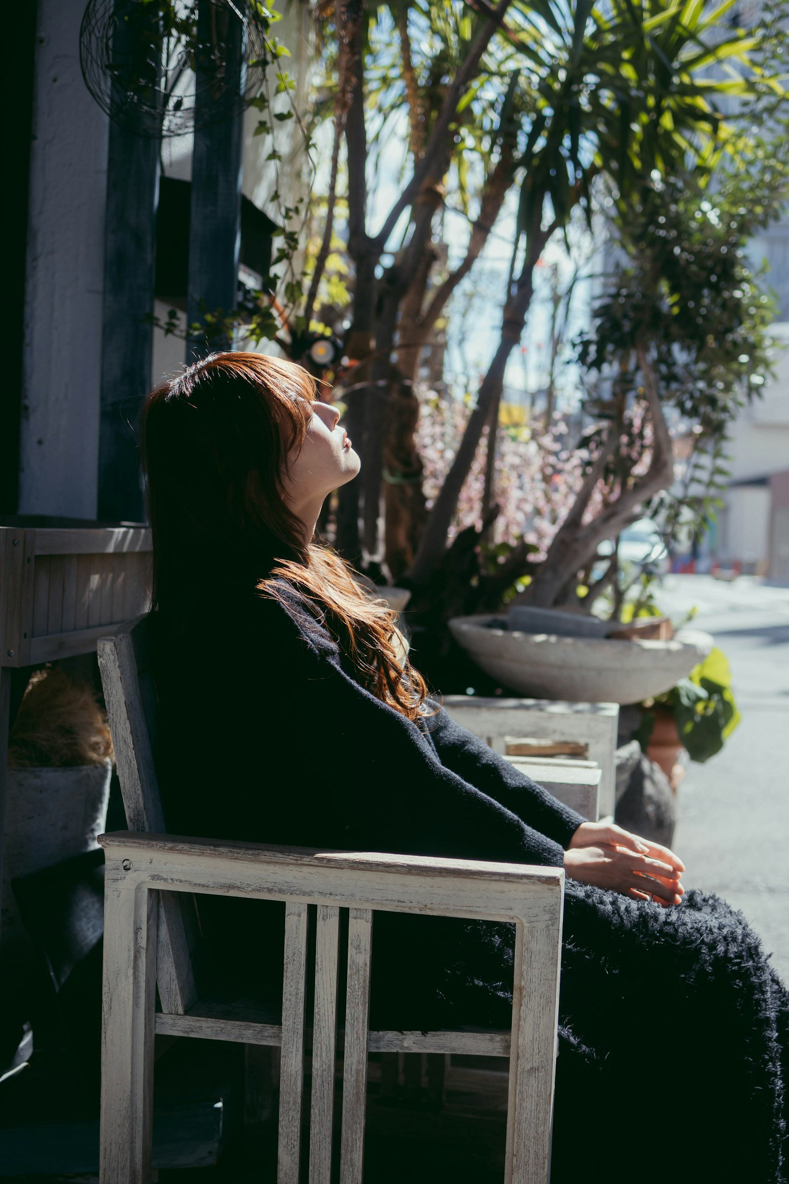Une femme assise sur une chaise profitant du soleil entourée de verdure luxuriante