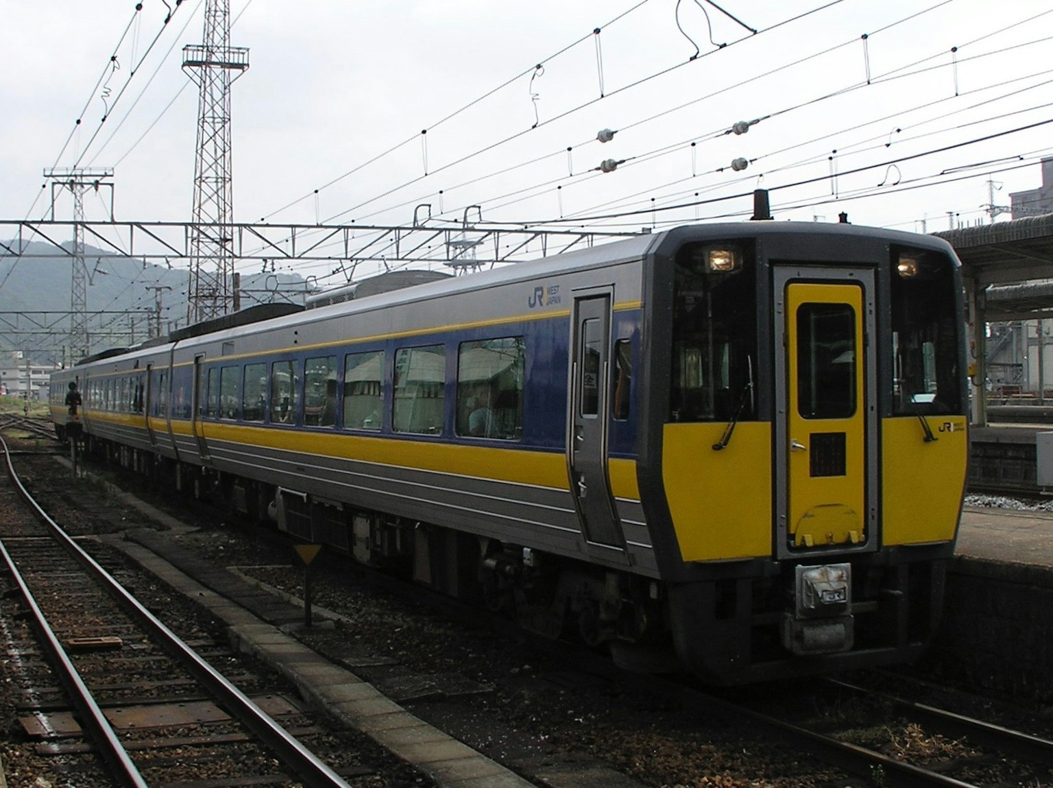 Ein Zug mit gelben und blauen Streifen, der an einem Bahnhof steht