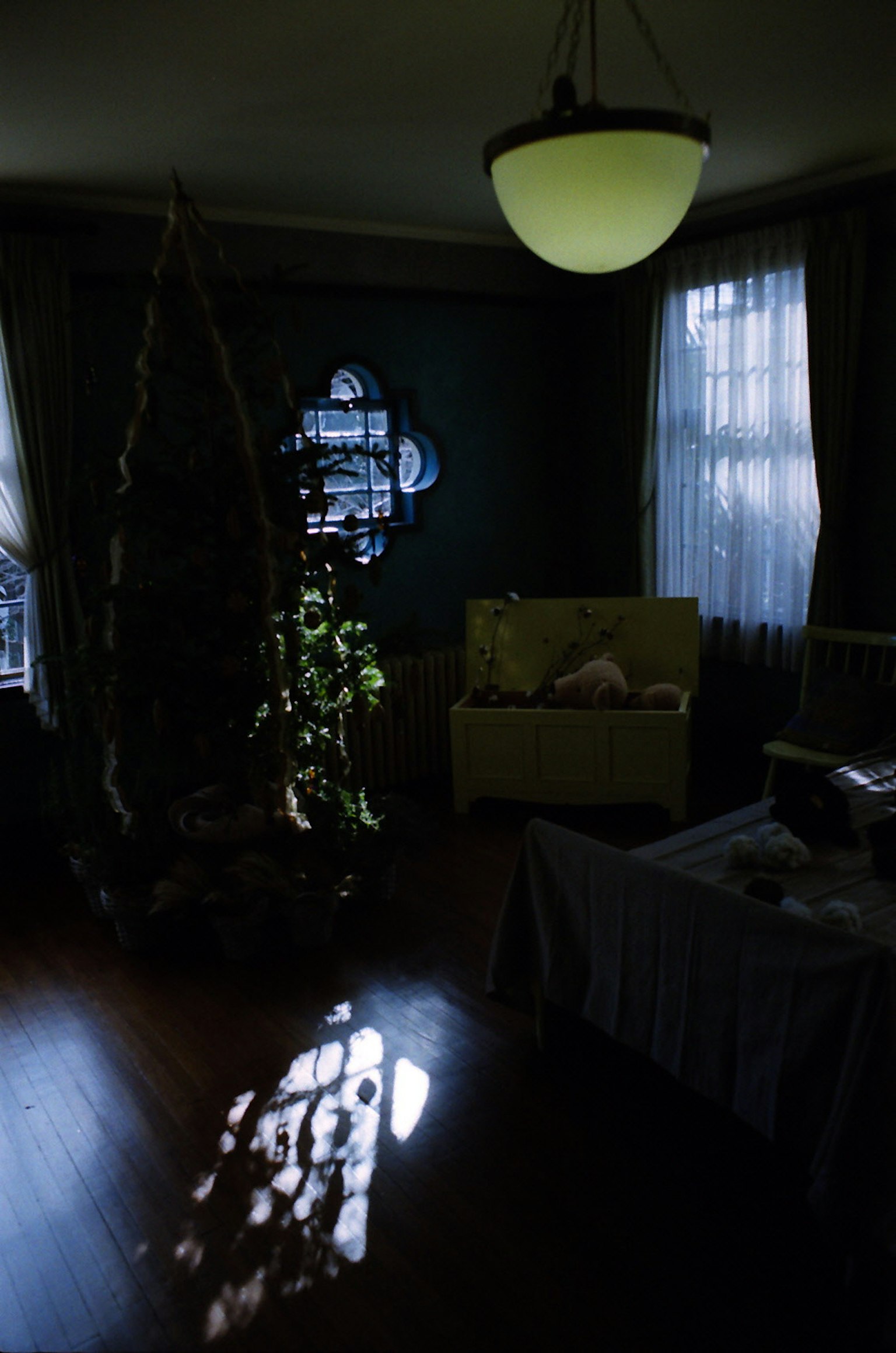 ห้องที่มีแสงน้อยมีโคมไฟสีเขียวและโซฟา แสงสะท้อนบนพื้นจากหน้าต่าง