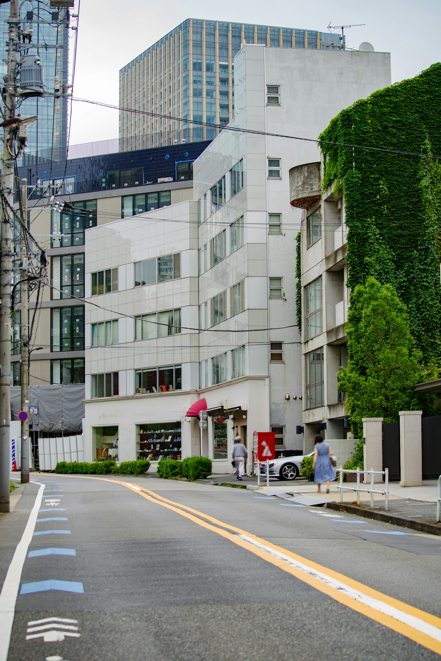 Vue de rue avec un bâtiment blanc entouré de verdure et de gratte-ciels