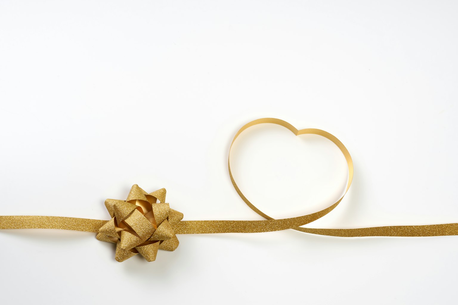 A golden ribbon with a bow and a heart-shaped ribbon on a white background