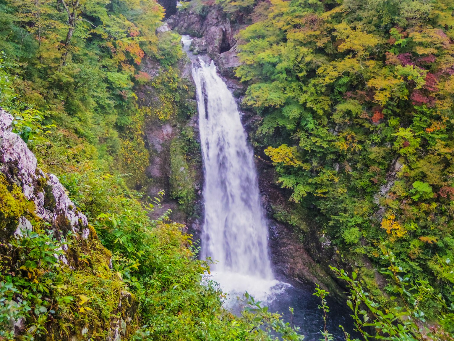 Air terjun indah dikelilingi pegunungan hijau