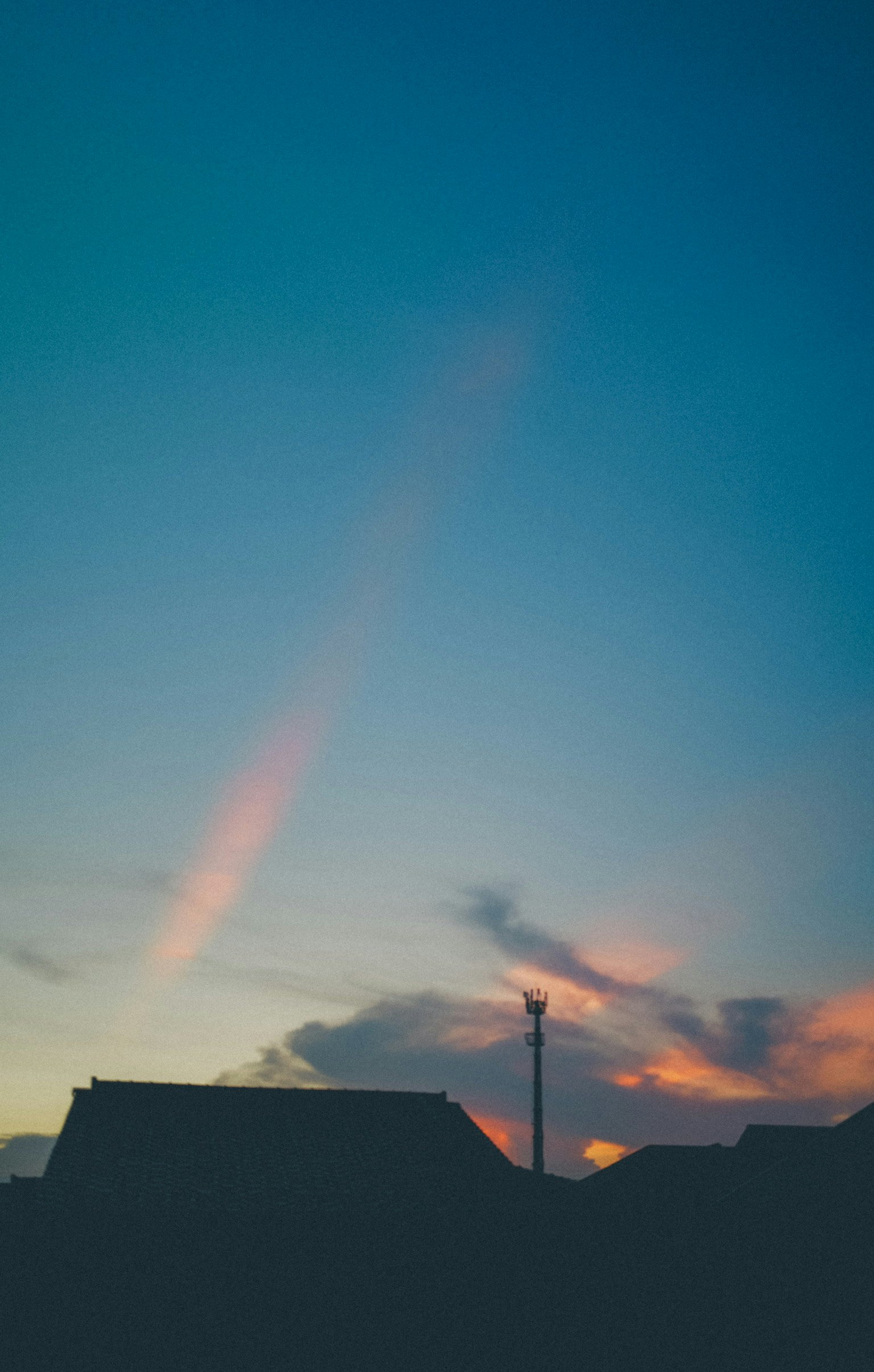 夕焼け空に伸びる飛行機雲のある住宅の屋根