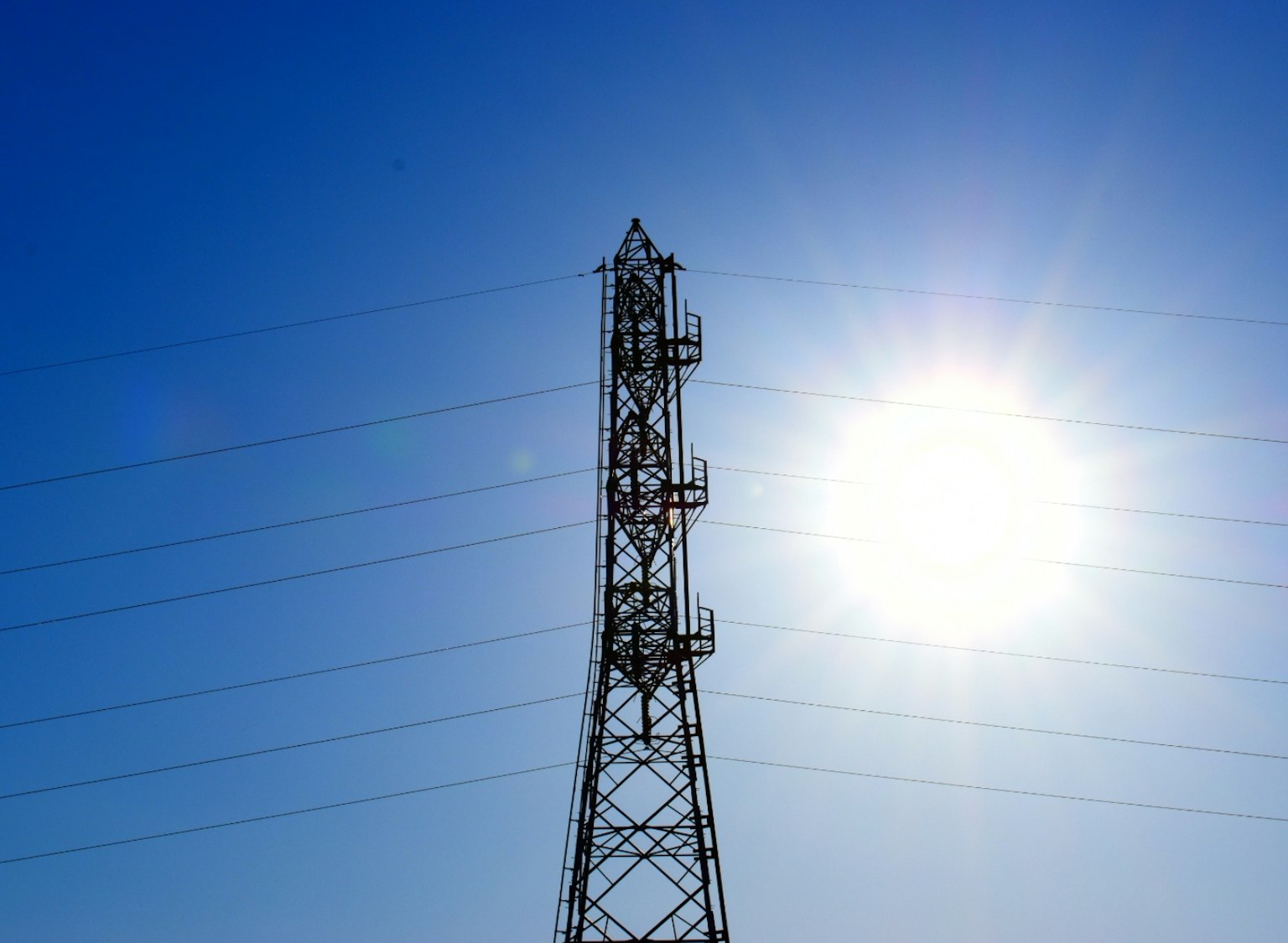 Una torre di trasmissione contro un cielo blu chiaro con il sole splendente