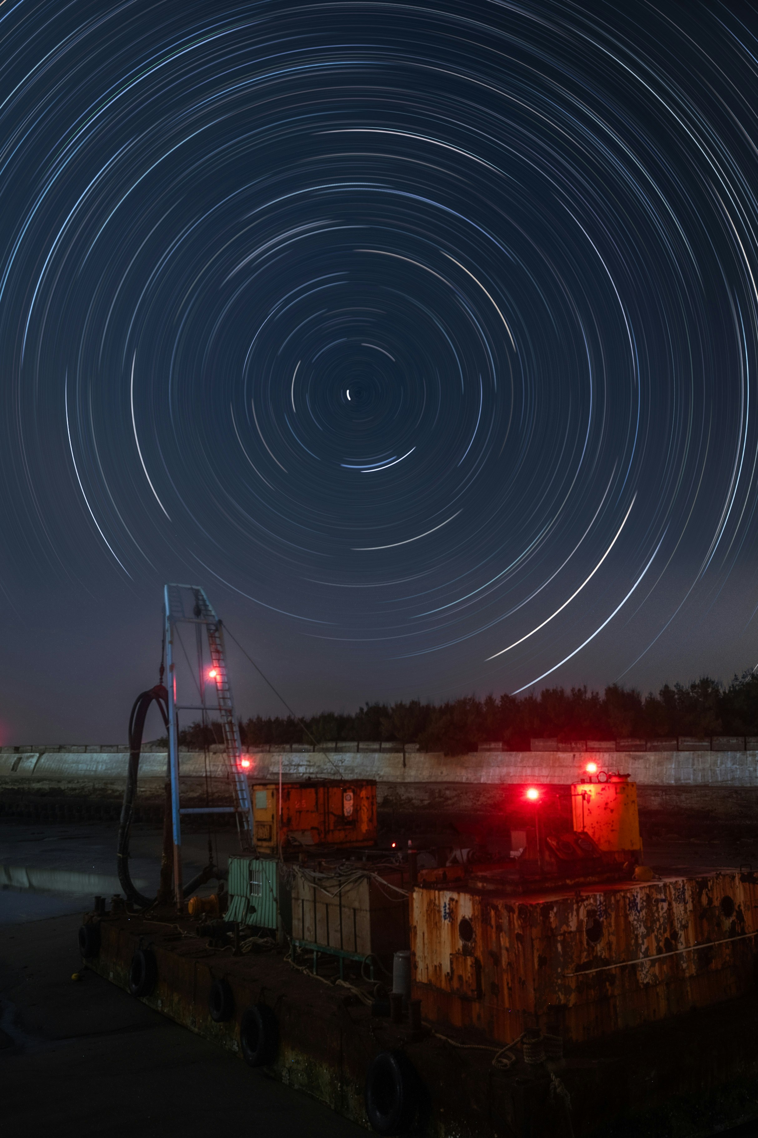 夜の港で回る星の軌跡と灯りのある作業船