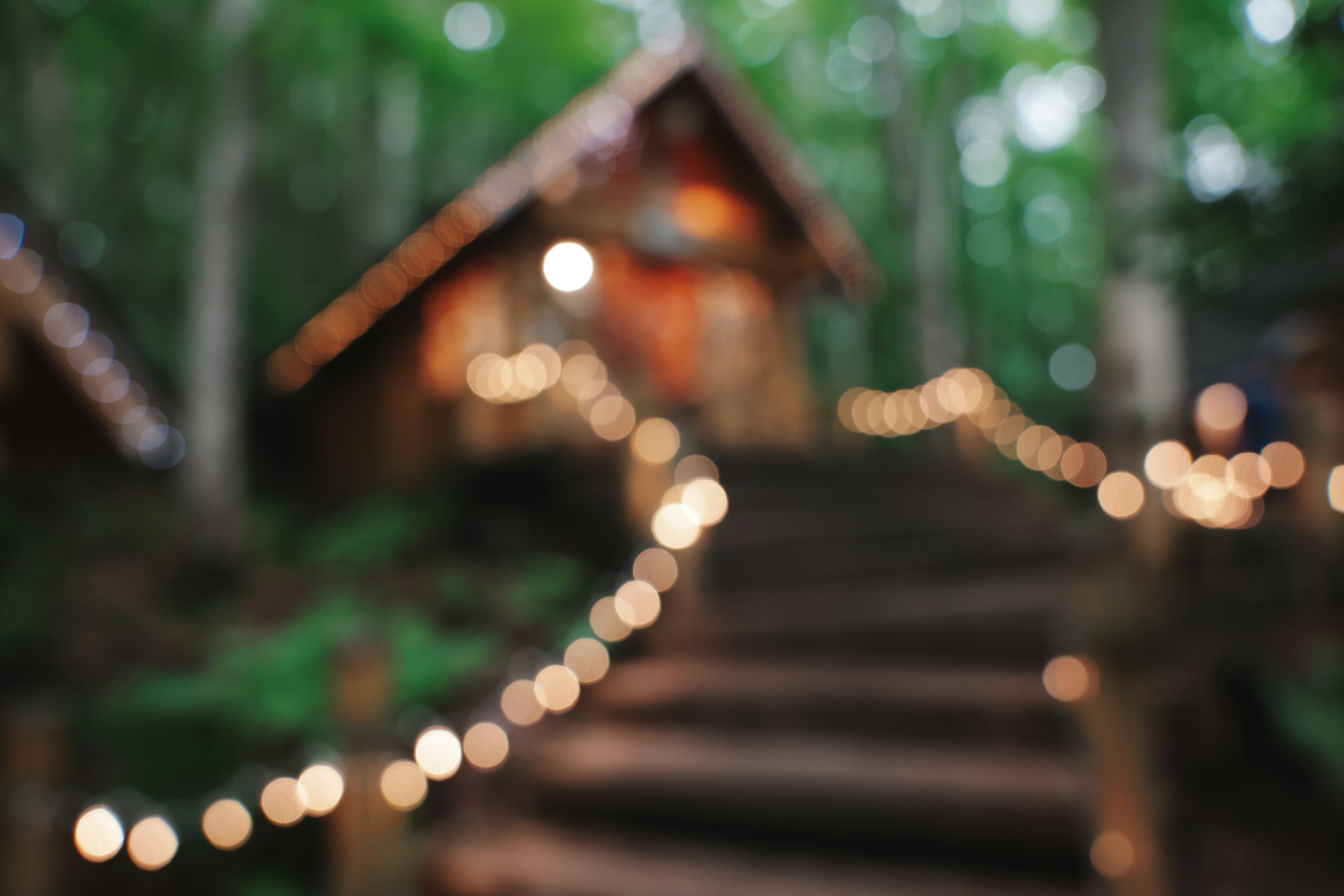 eine kleine Hütte am Ende einer Treppe mit Lichtern im Wald