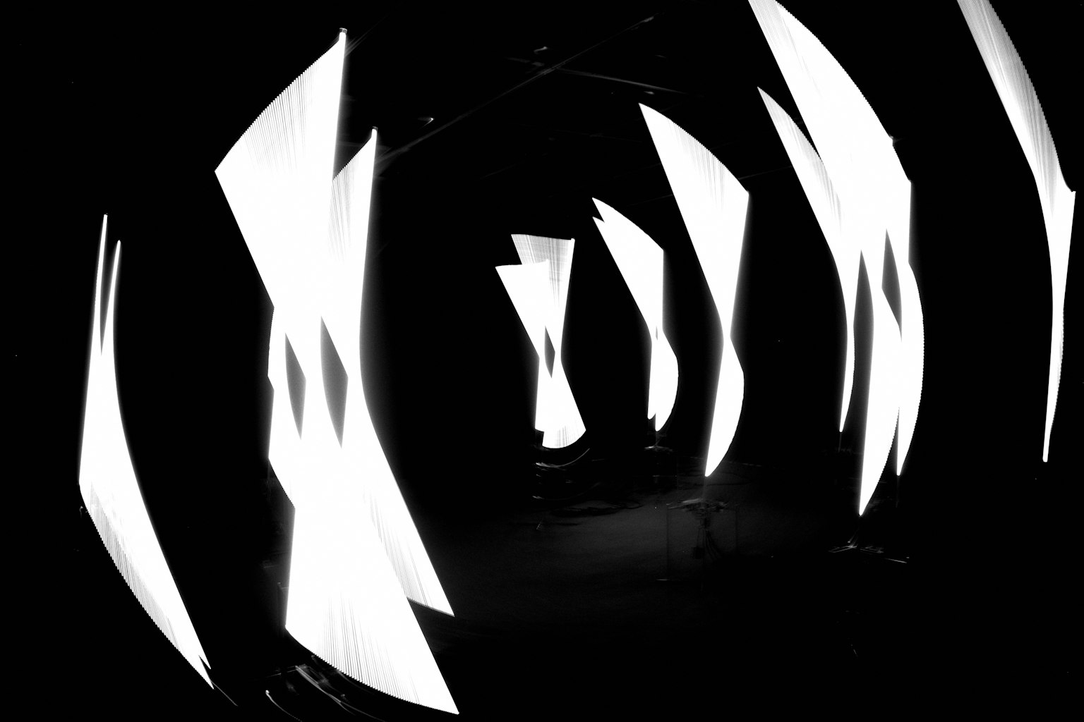 暗いトンネルに浮かぶ白い光の形状が特徴的なアートインスタレーション