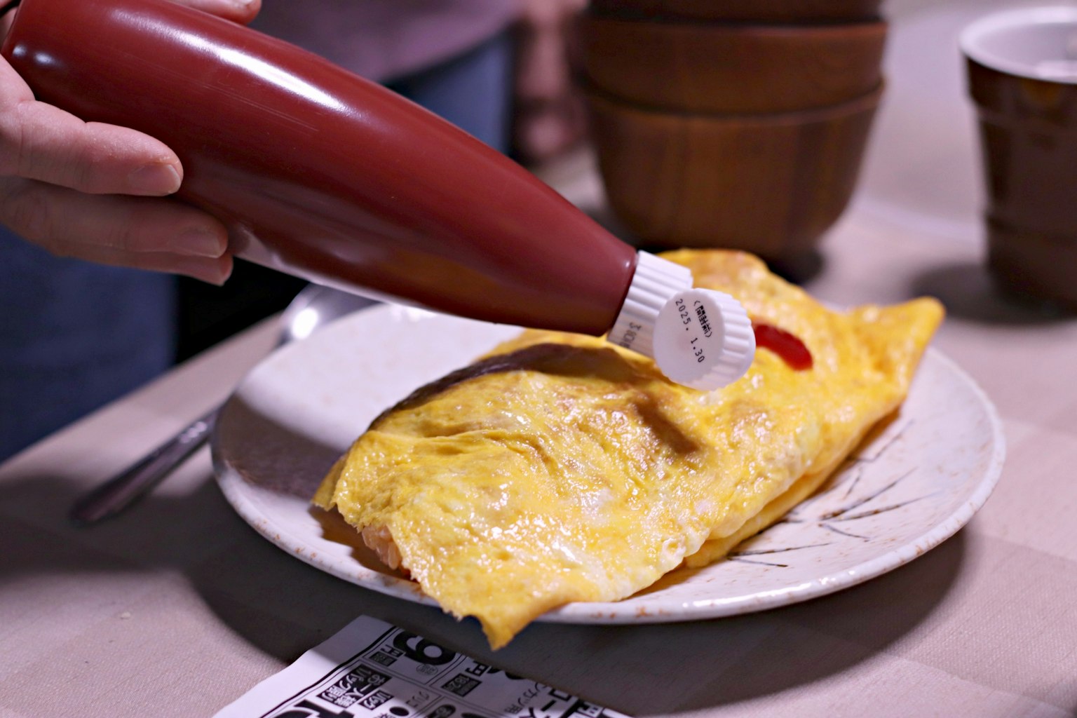 Mano exprimiendo ketchup sobre una tortilla en un plato