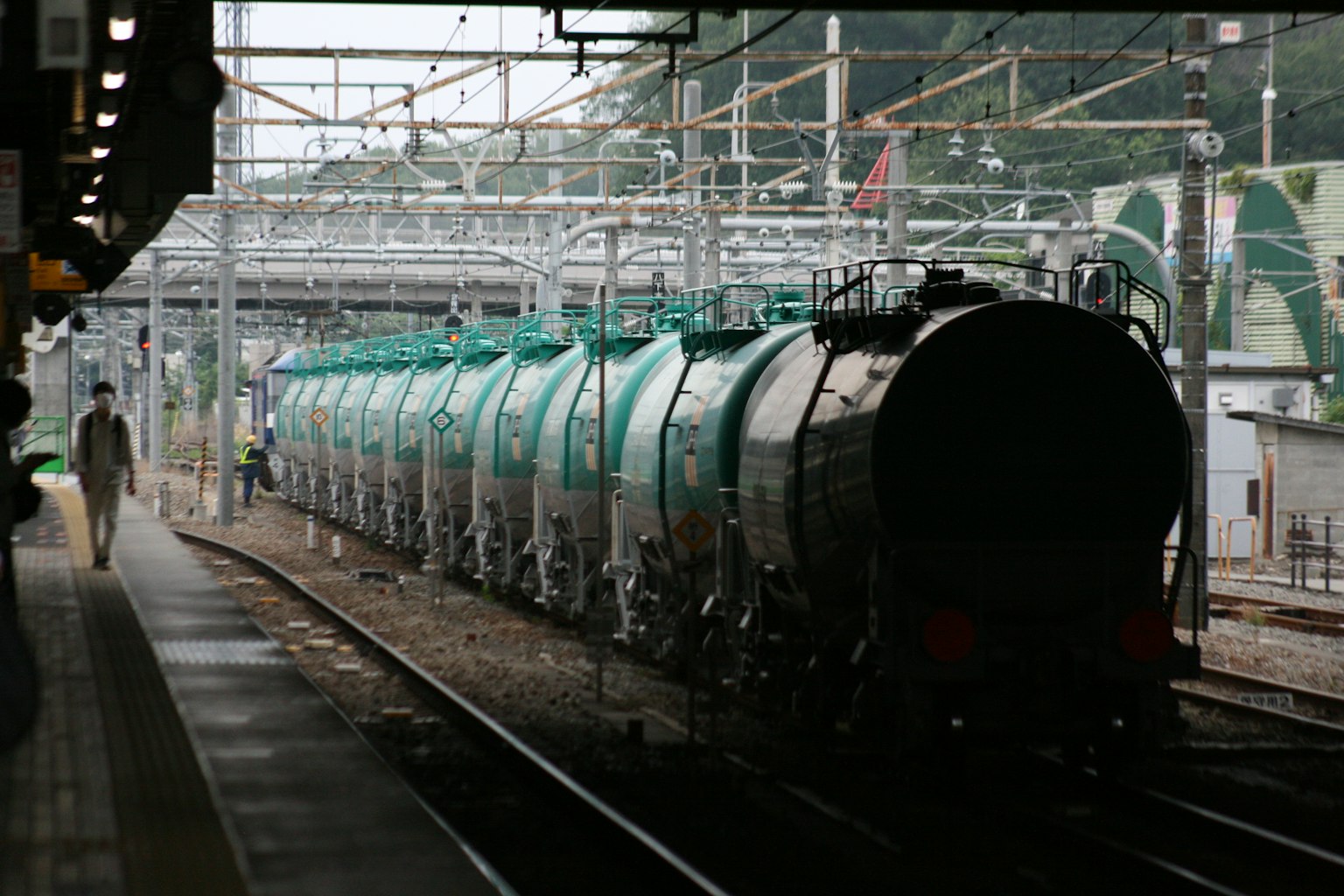 ภาพของรถไฟขนส่งที่สถานีโดยมีรถถังสีเขียวเรียงราย