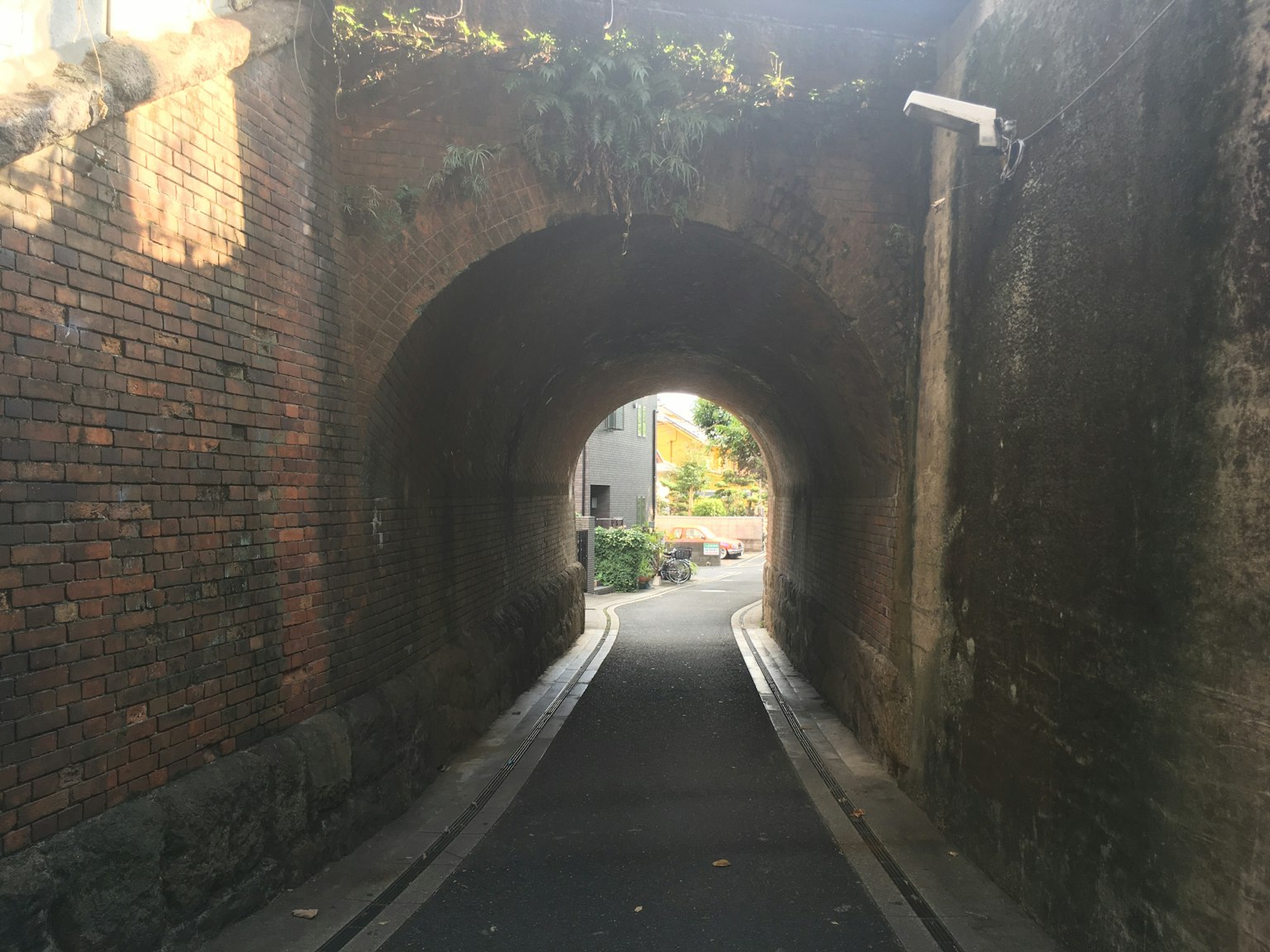 Blick auf einen Backsteintunnel mit einer Straße darin heller Ausgang sichtbar