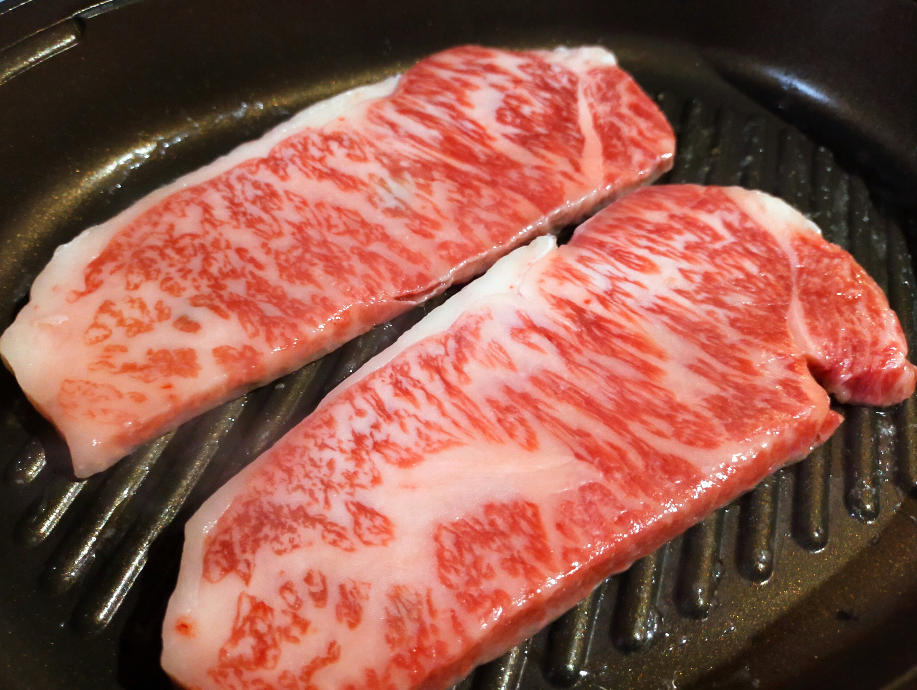 bít tết wagyu vân cẩm thạch đang nướng trên bếp nóng