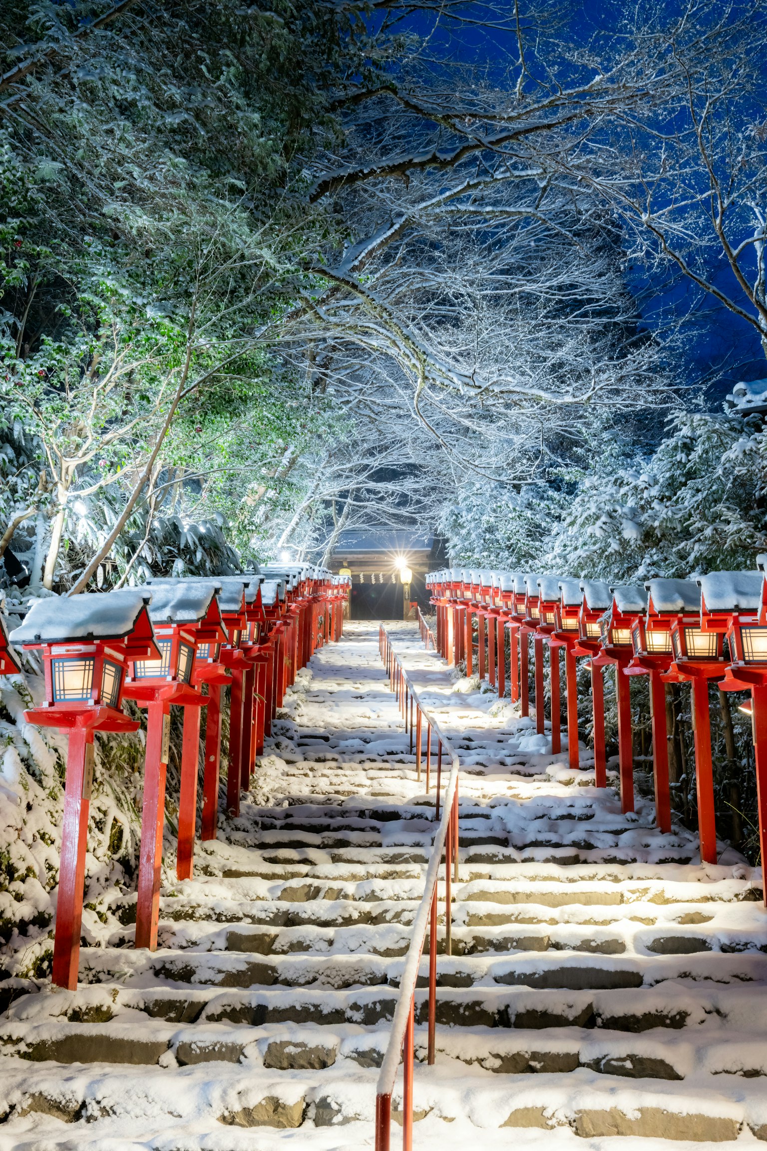 Snow-covered stairs with red lanterns lining the path