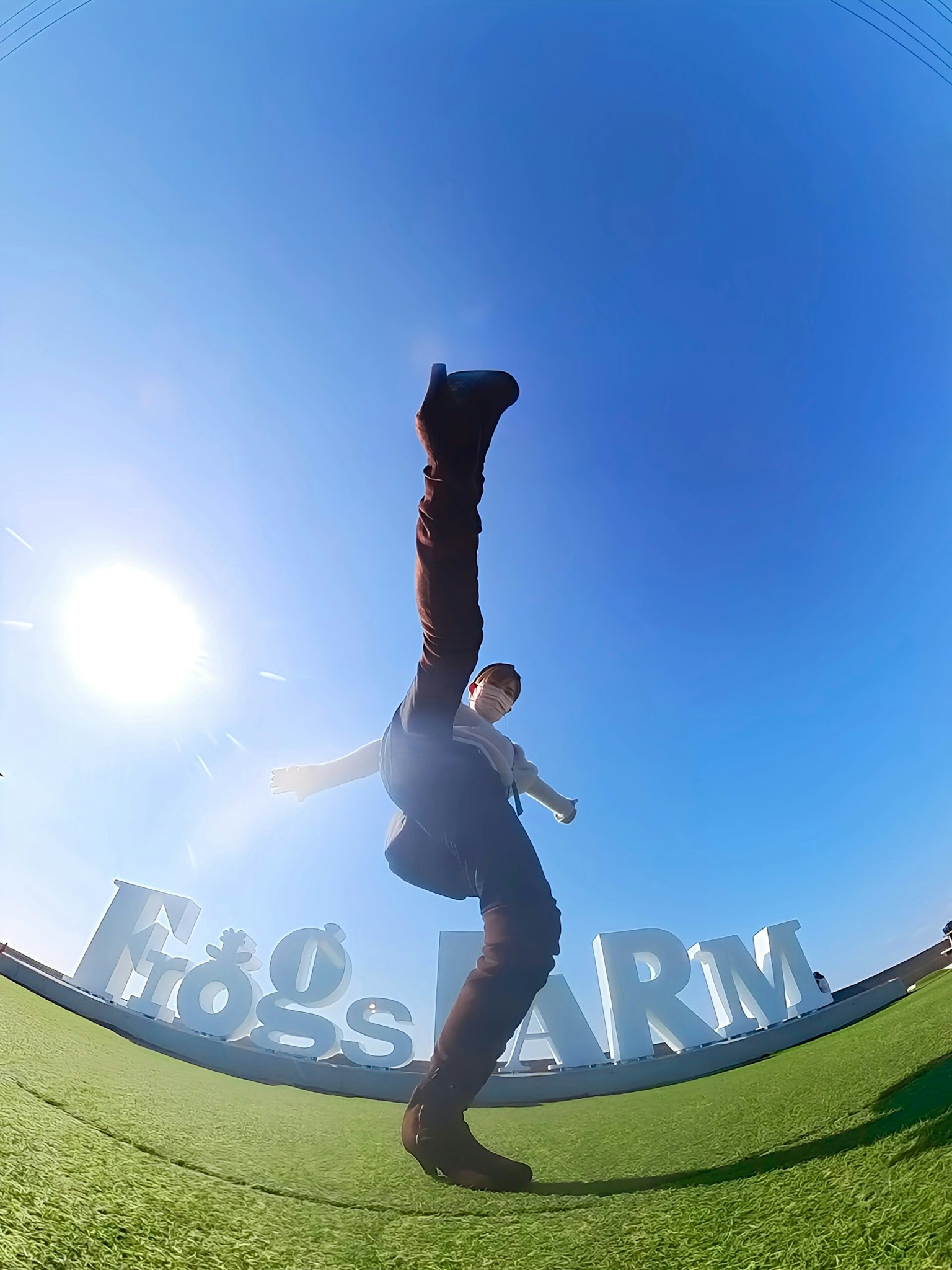 Ein Mann in einer einzigartigen Pose auf einem Bein unter einem blauen Himmel mit großen Buchstaben im Hintergrund