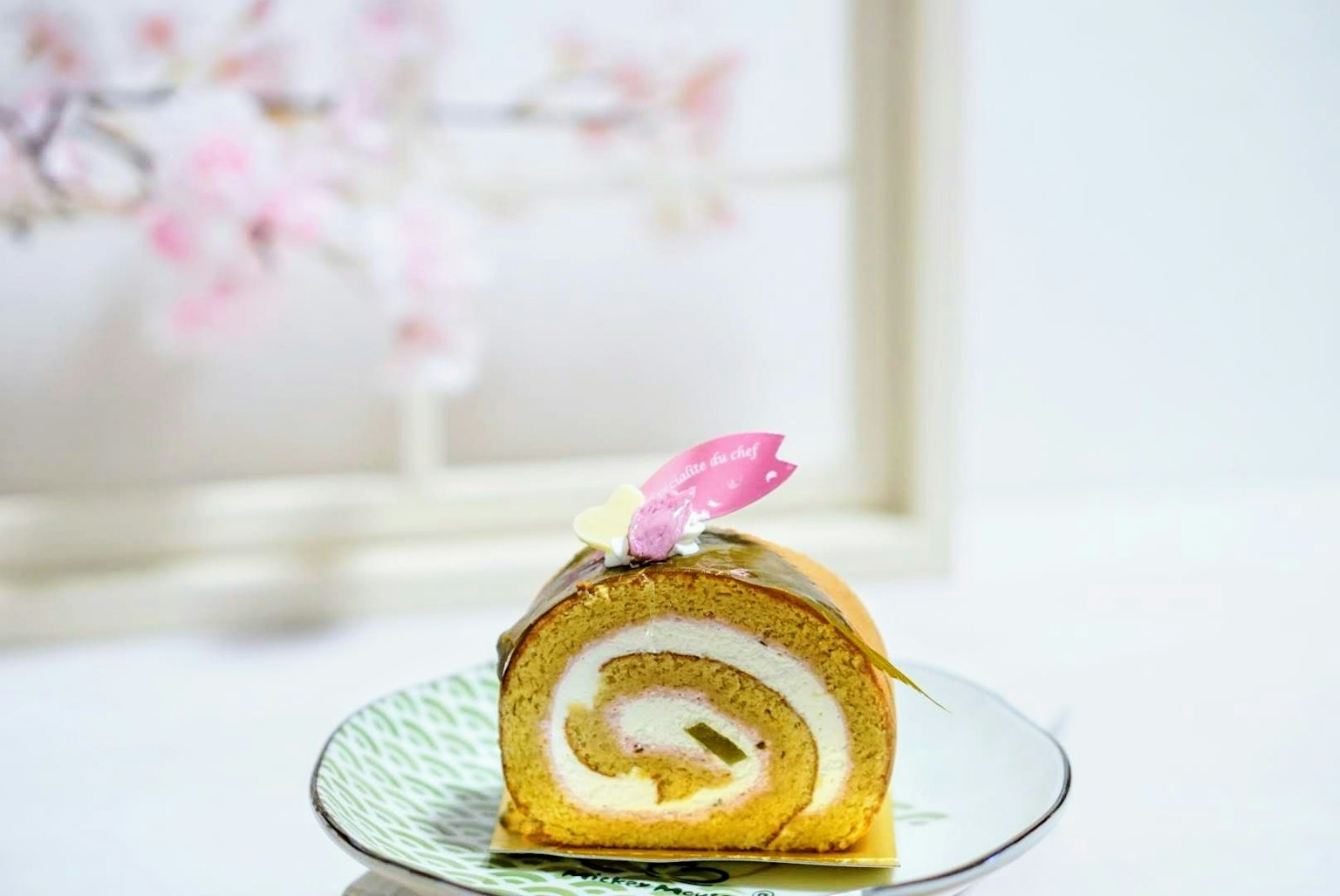 Ein wunderschön dekorierter Rollkuchen mit einer rosa Blume darauf