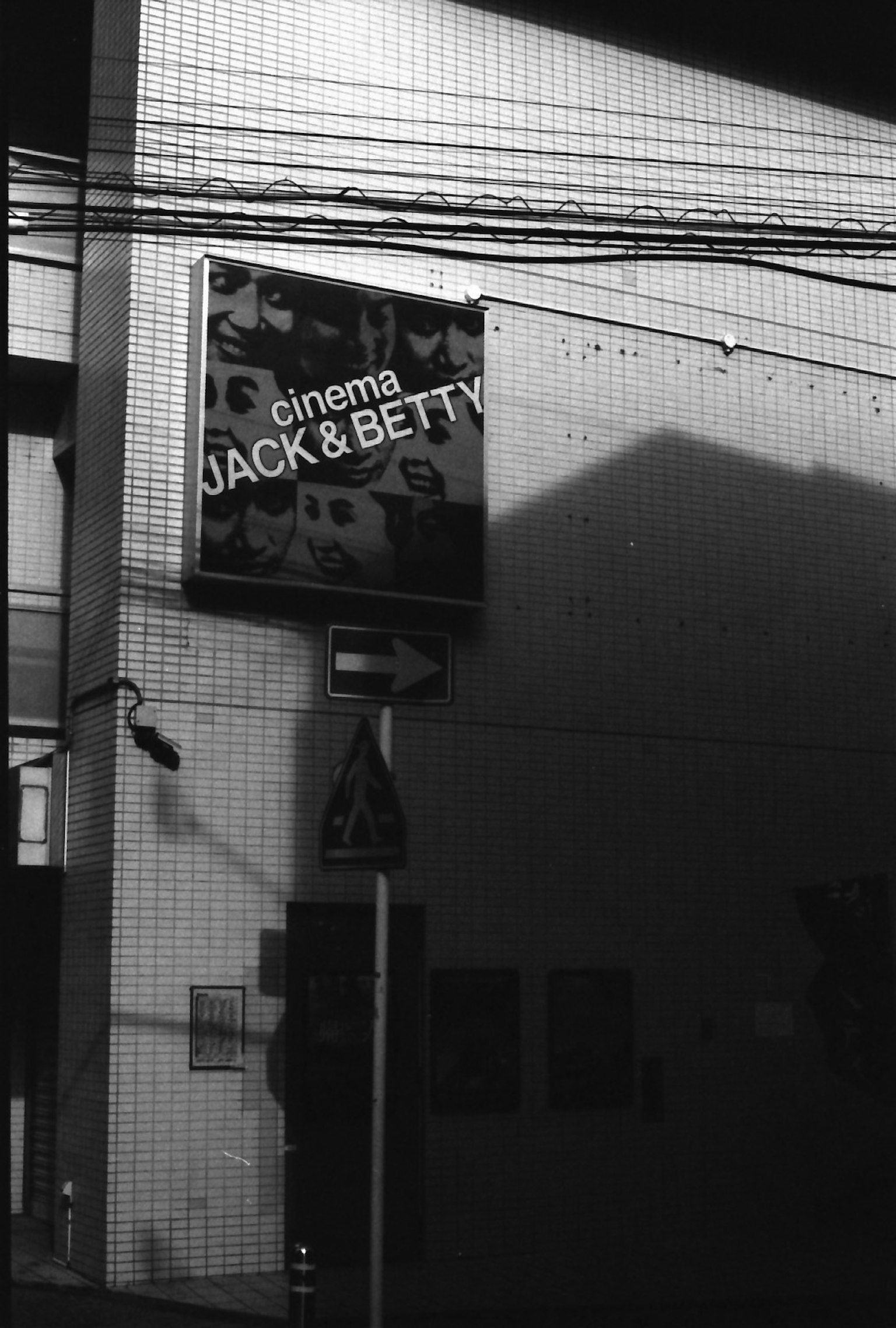 Pemandangan jalan hitam putih menampilkan papan sinema Jack & Betty