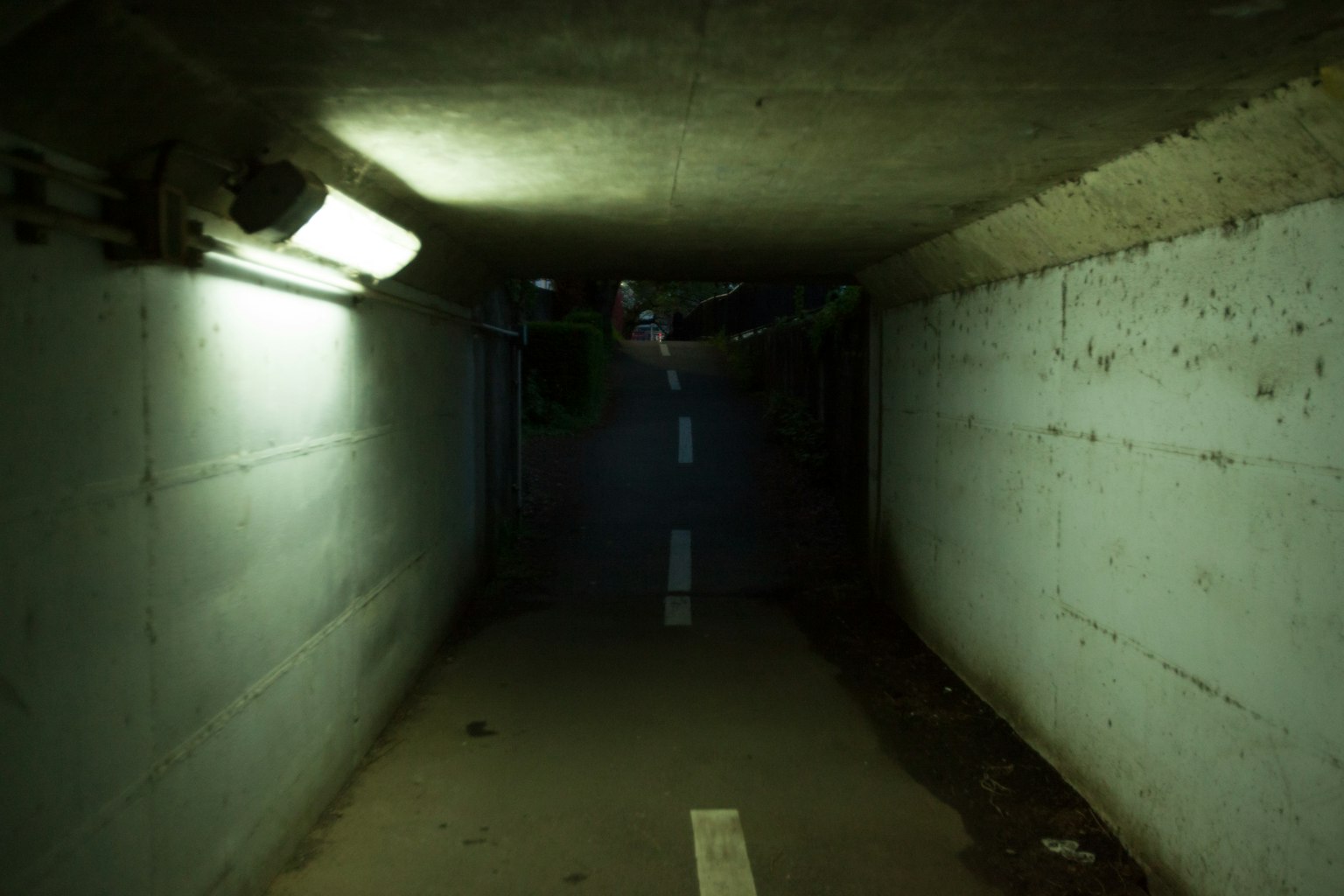 Inneres eines schwach beleuchteten Tunnels mit blauen Wänden und einer weißen Linie auf dem Boden