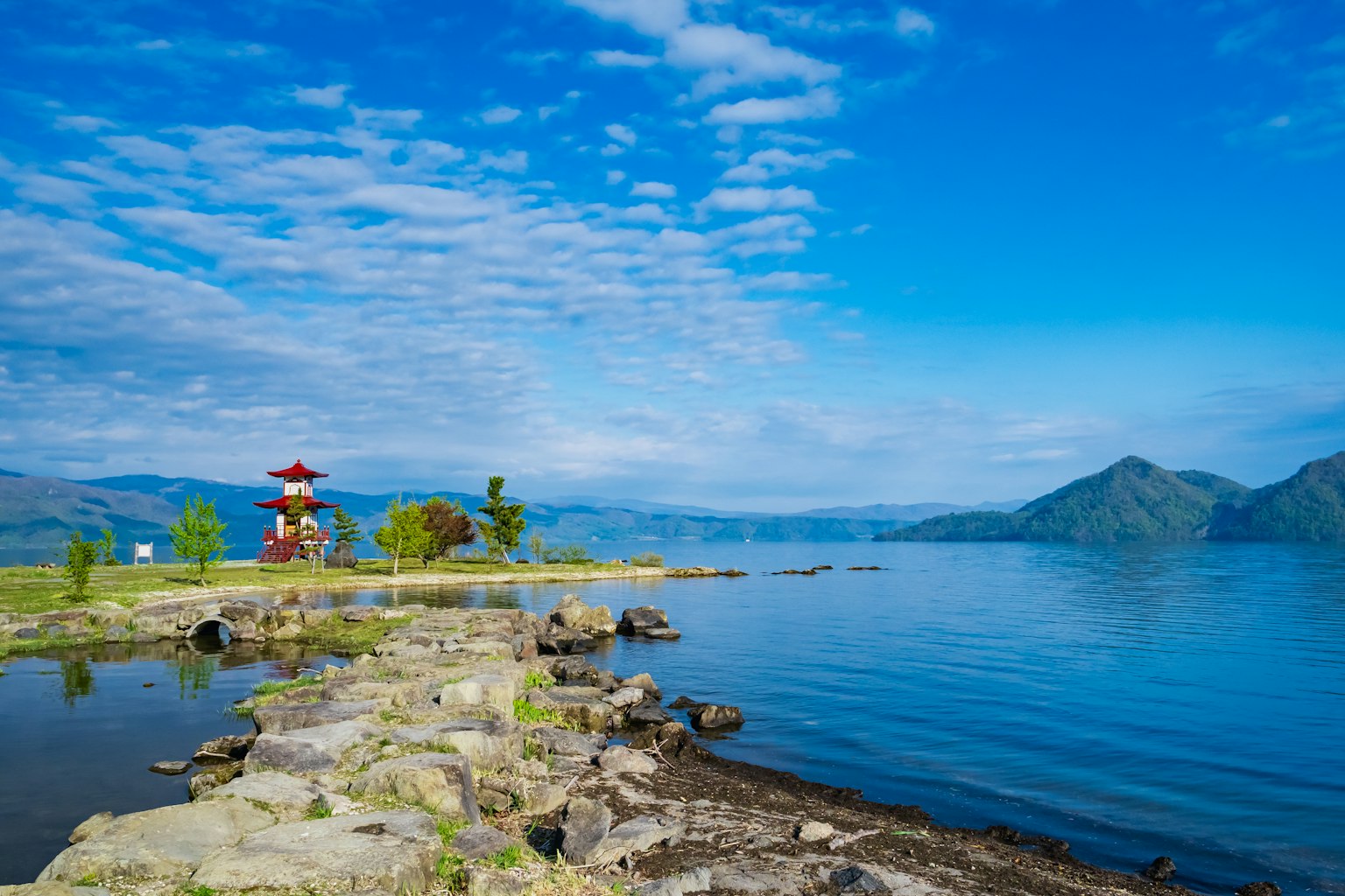Scenic view of a lake with a red pagoda and blue sky