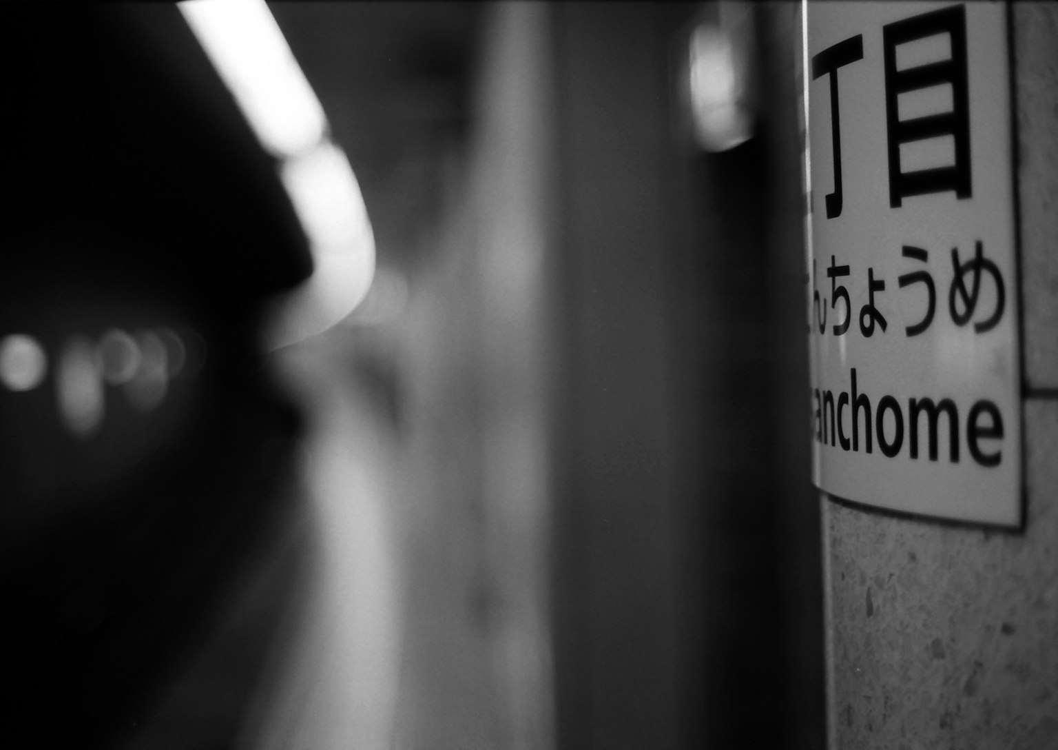 Immagine in bianco e nero di un segnale di stazione della metropolitana con il nome di una città e di una stazione
