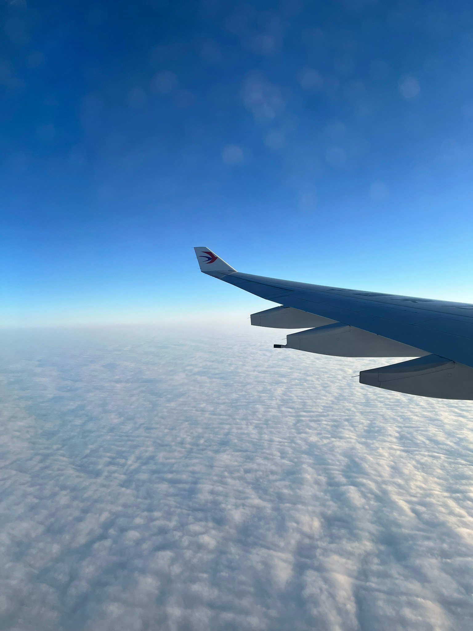 Ala di un aereo sopra nuvole soffici sotto un cielo azzurro