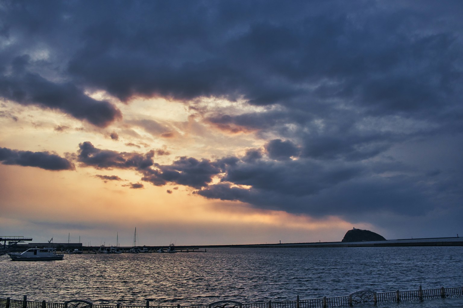 Seascape at sunset with boats and dark clouds