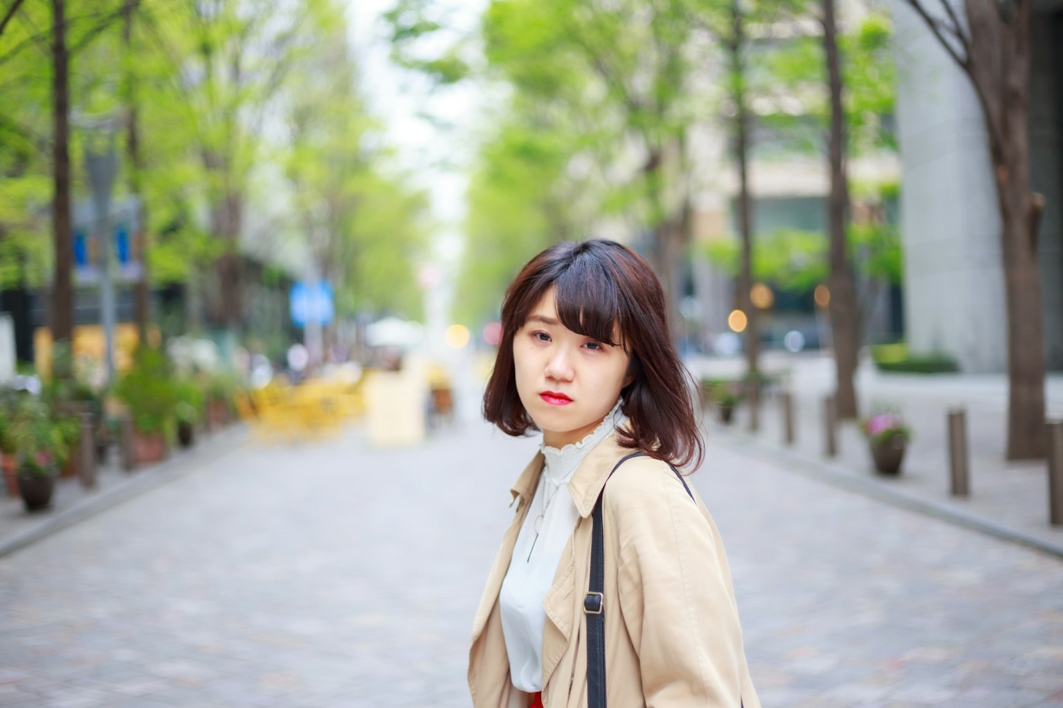나무가 늘어선 거리에서 걷고 있는 여성의 초상
