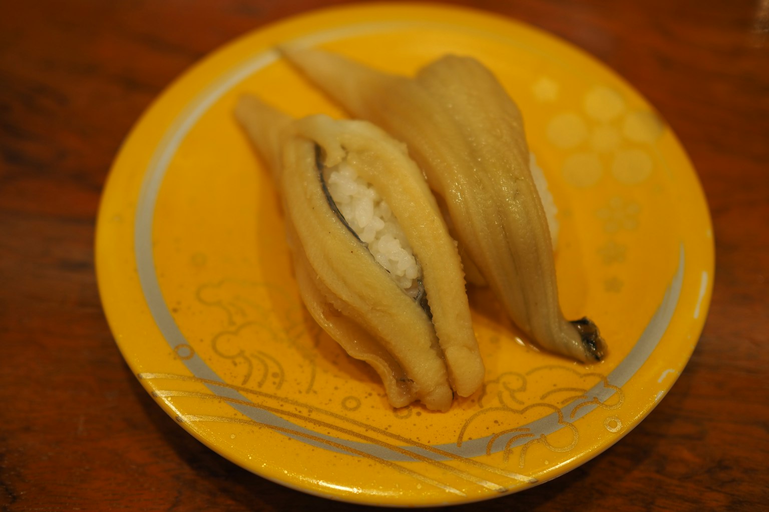 Sushi en un plato amarillo con arroz envuelto en pescado